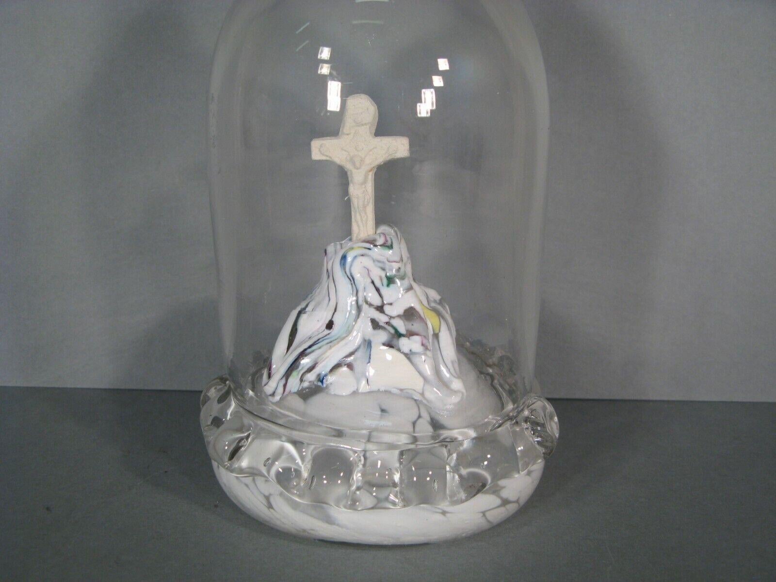 This intriguing and captivating crucifix is crafted from berlingot glass and possibly plaster for the cross, encased in a protective blown glass dome topped with a cross. This devotional piece dates back to the late 19th to early 20th