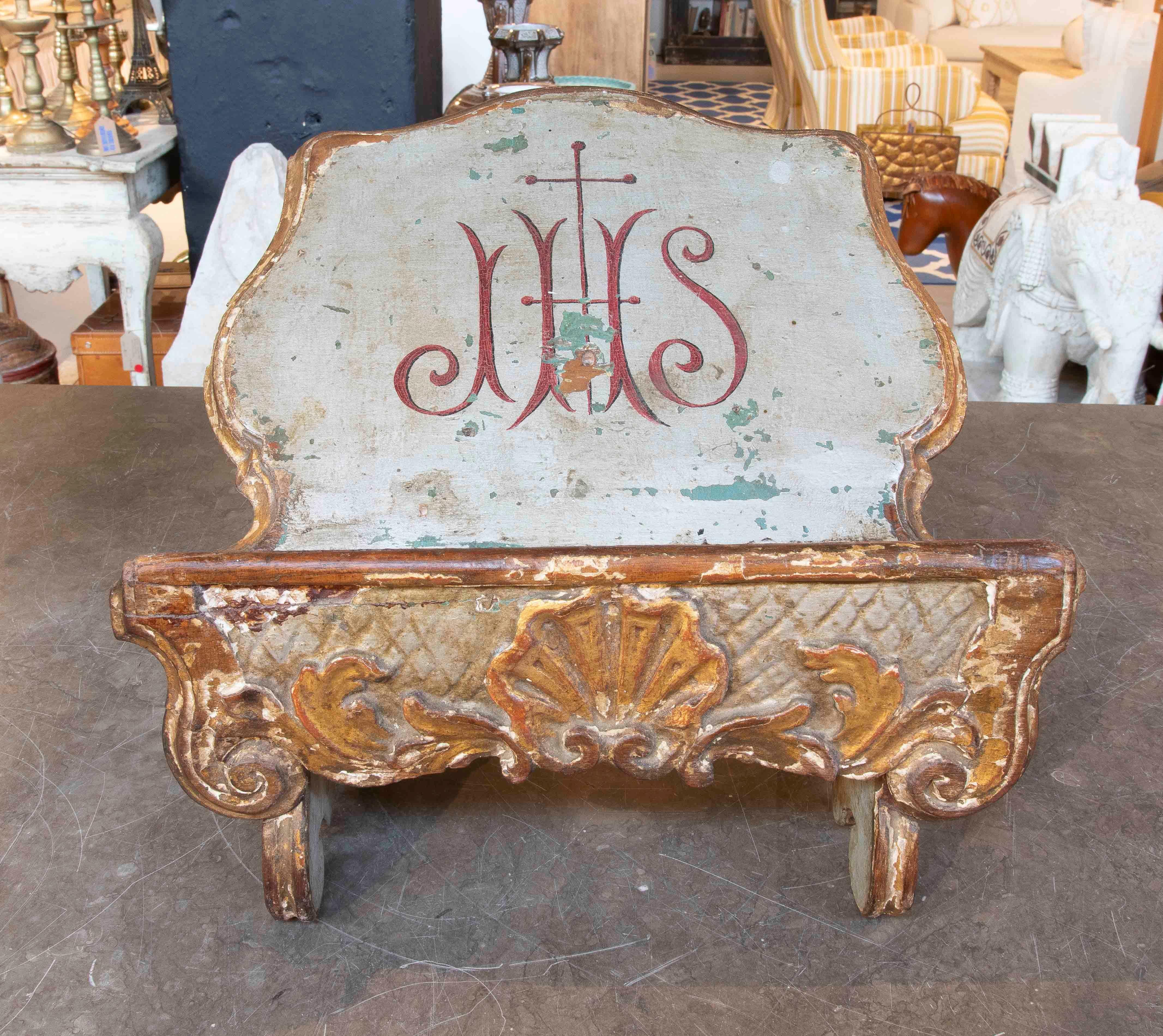 Antique Baroque-style liturgical lectern, made of carved and polychrome wood with gilded details. The piece features a curved backrest with the monogram 