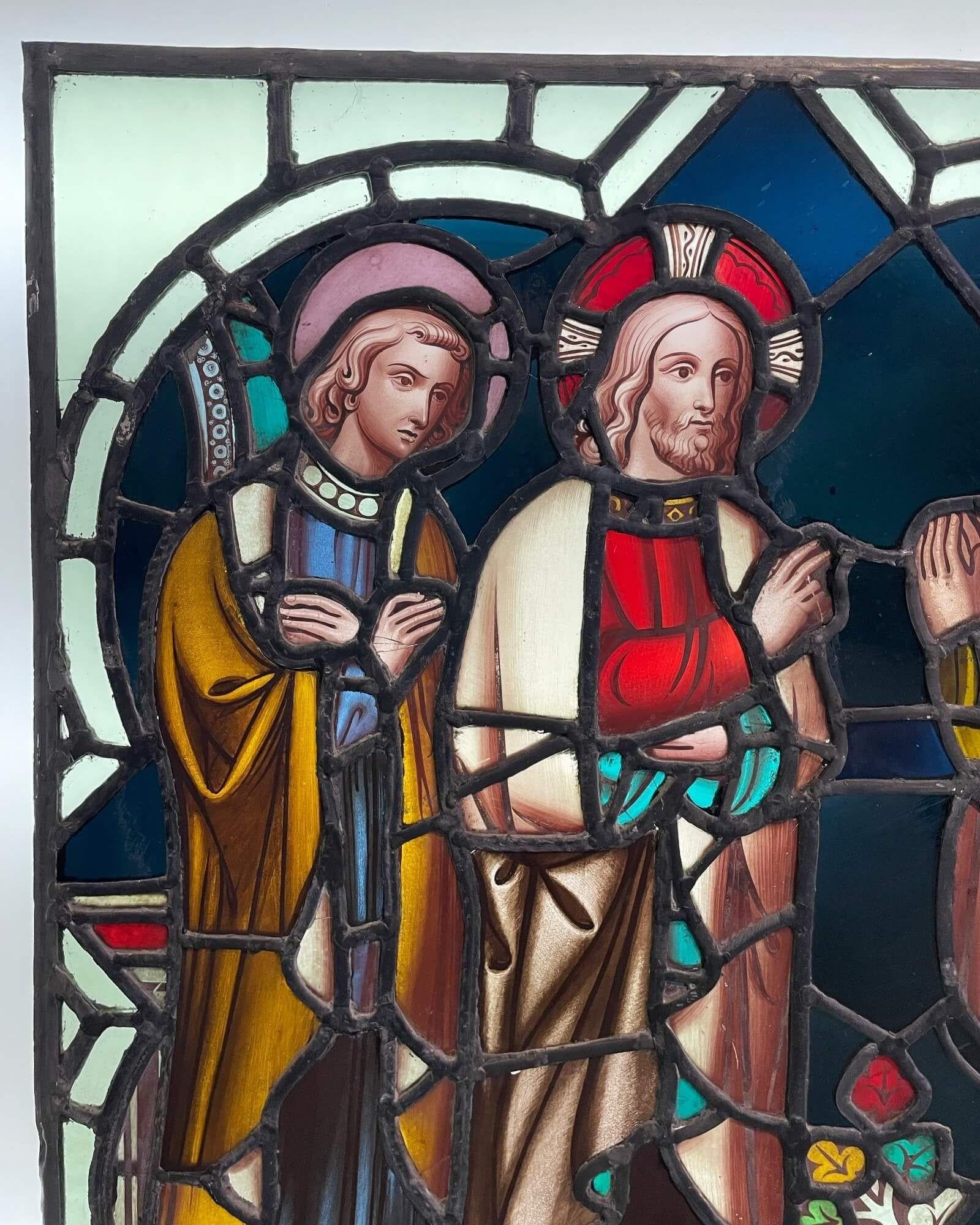 An early 20th century antique religious stained glass window circa 1900. Depicting an ecclesiastical scene, thought to be Jesus with two disciples, the subject is stunningly captured across and array of vibrant colours, skilfully crafted at the hand