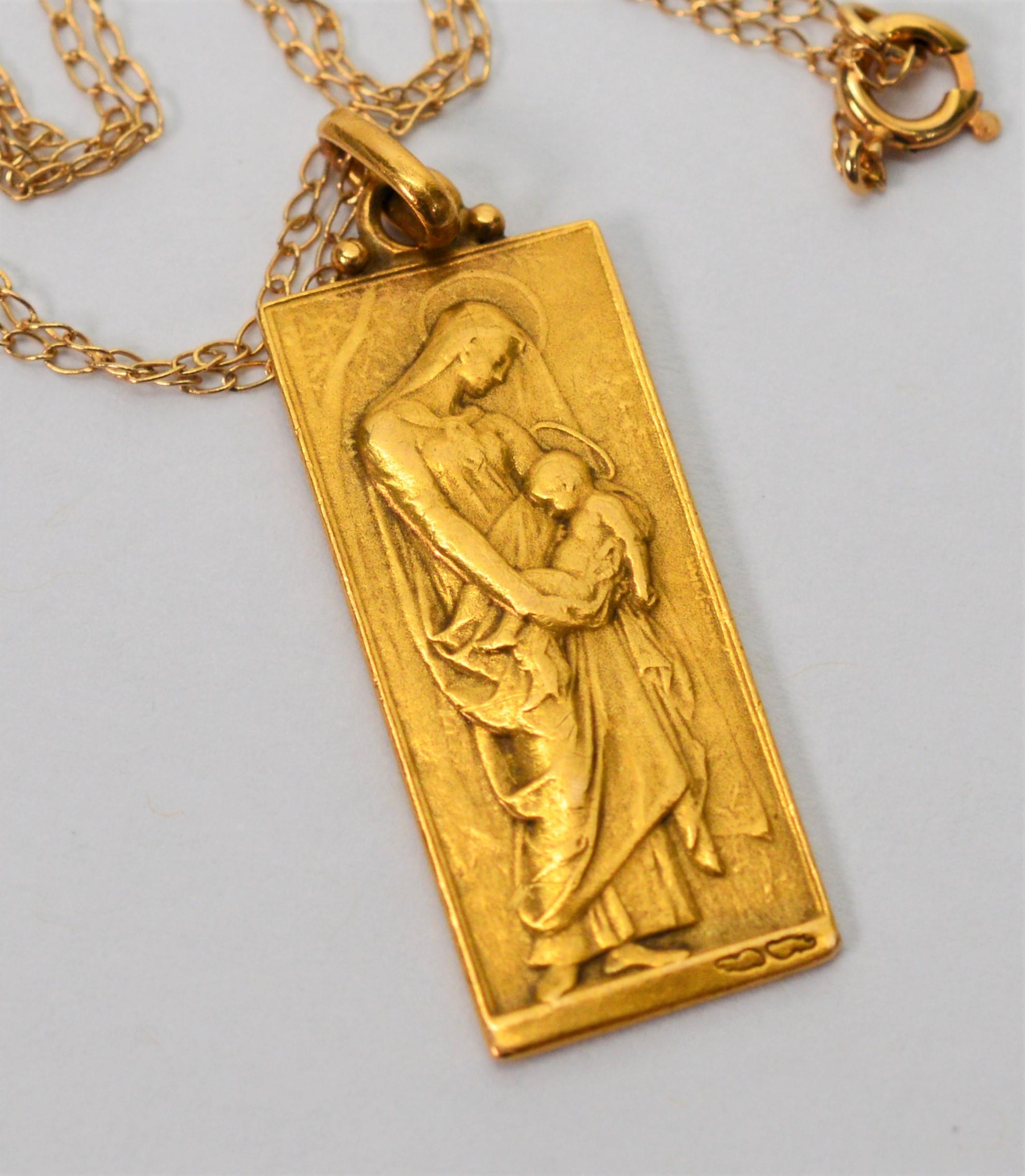 Art Nouveau , circa 1910 and signed, this rare religious French plaque medal pendant in fourteen karat yellow gold has a detailed image of mother and child on front and a rising cross on the reverse.  The medal pendant measures 1 x 3/8 inch and is