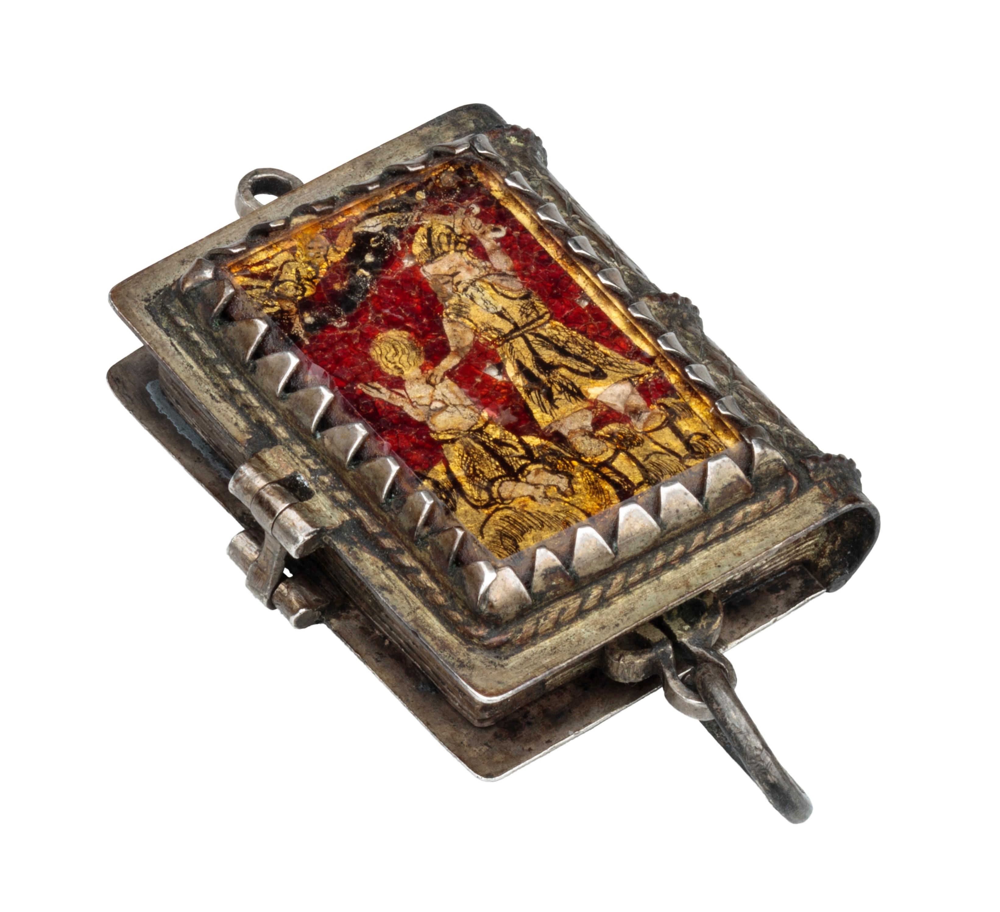 RELIQUARY PENDANT IN BOOK FORM 
Probably southern Germany, 1630–40 
Gilded silver, verre églomisé 
Weight 13.2 grams; dimensions 42 × 25 × 12 mm; opens to 40 mm 

Gilded silver pendant in book form with hinged, lid, corded wire surround, and