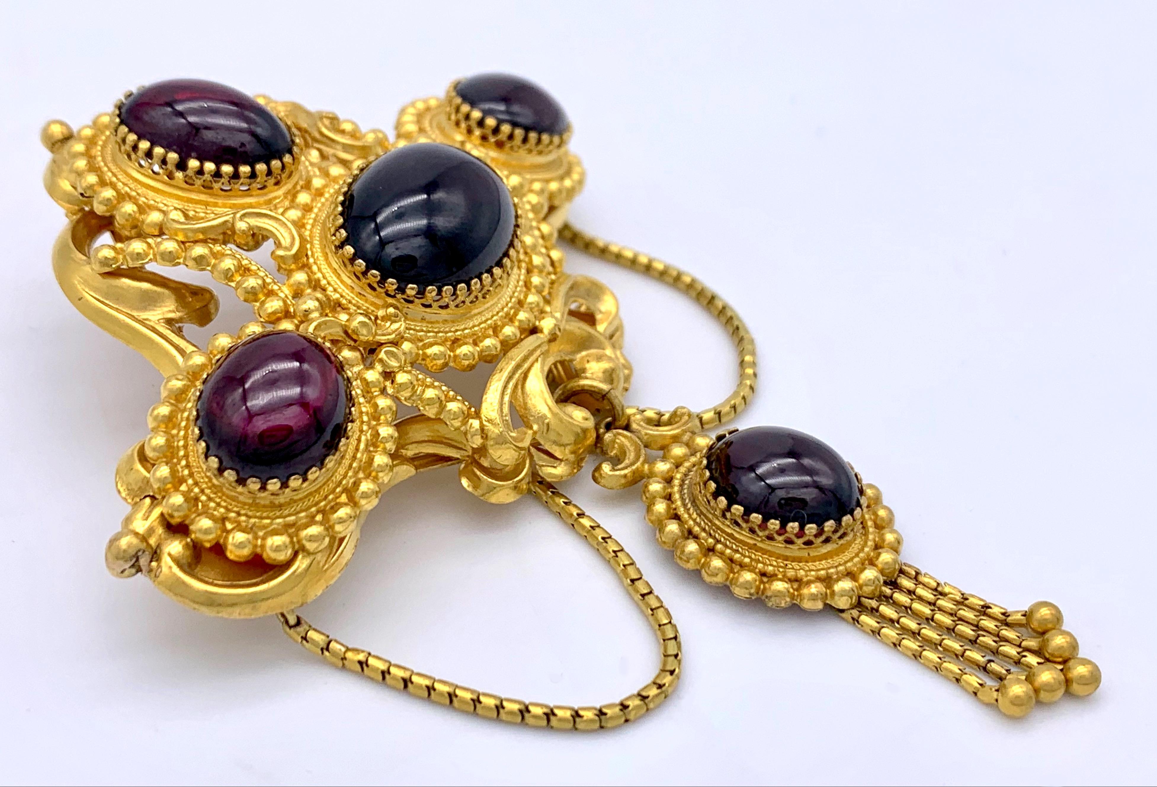 Absolute stunning example of a renaissance revival piece of jewellery executed around 1850 in 14 karat gold. The brooch is set with with 5  oval almandine garnet cabochons. Two gold chains and an articulated pendant with five dangling tassels,