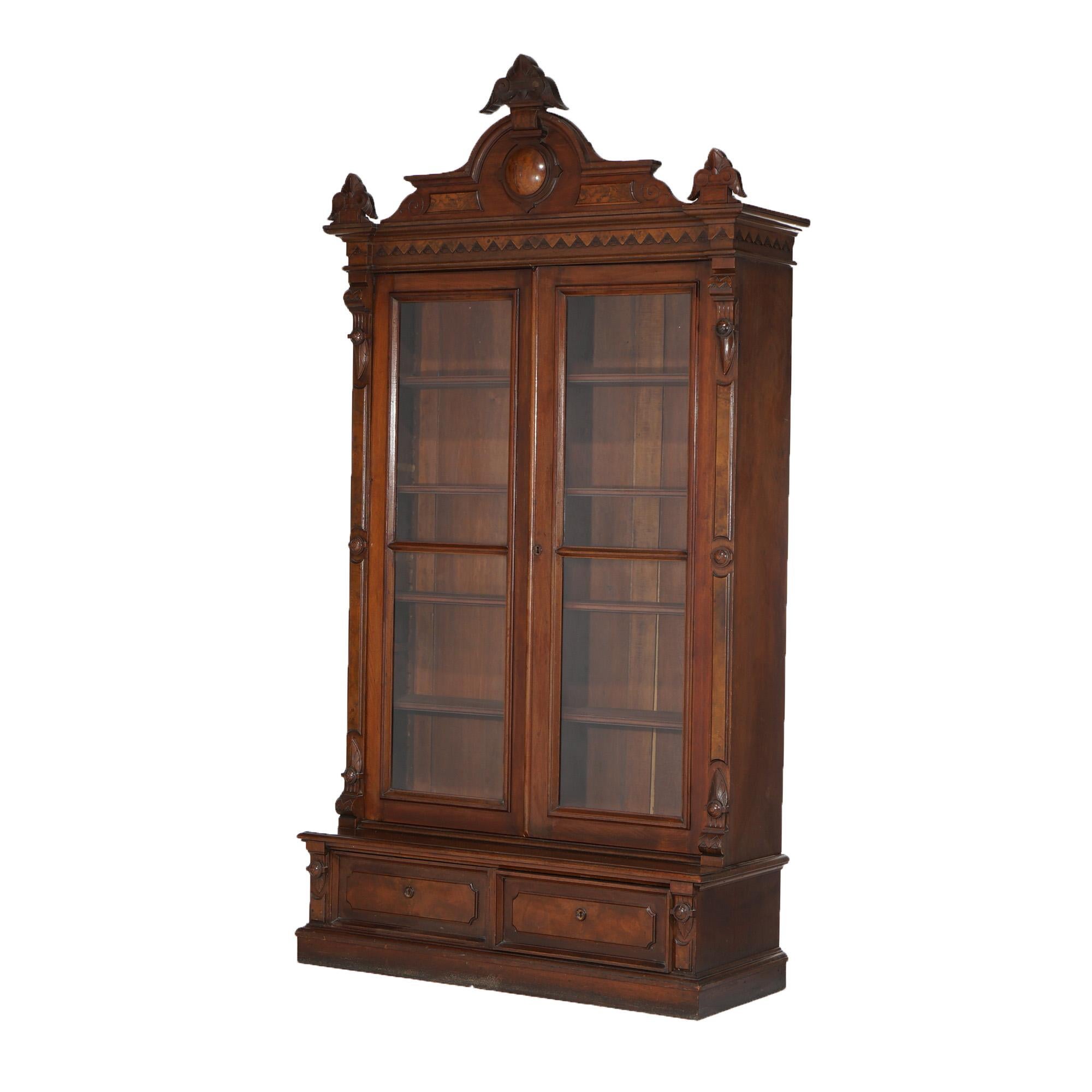 ***Ask About Reduced In-House Shipping Rates - Reliable Service & Fully Insured***
An antique Renaissance Revival enclosed bookcase offers walnut and burl construction with carved foliate crest over case with double glass doors opening to shelved