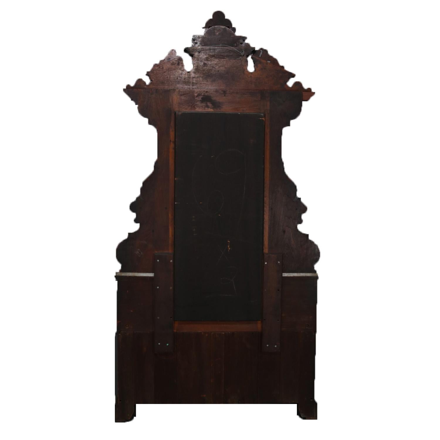 An antique Renaissance Revival drop front features walnut construction with burl panels and having carved broken arch mirror with central shield and foliate form cartouche and flanked by marble top glove boxes with drop center marble top base having