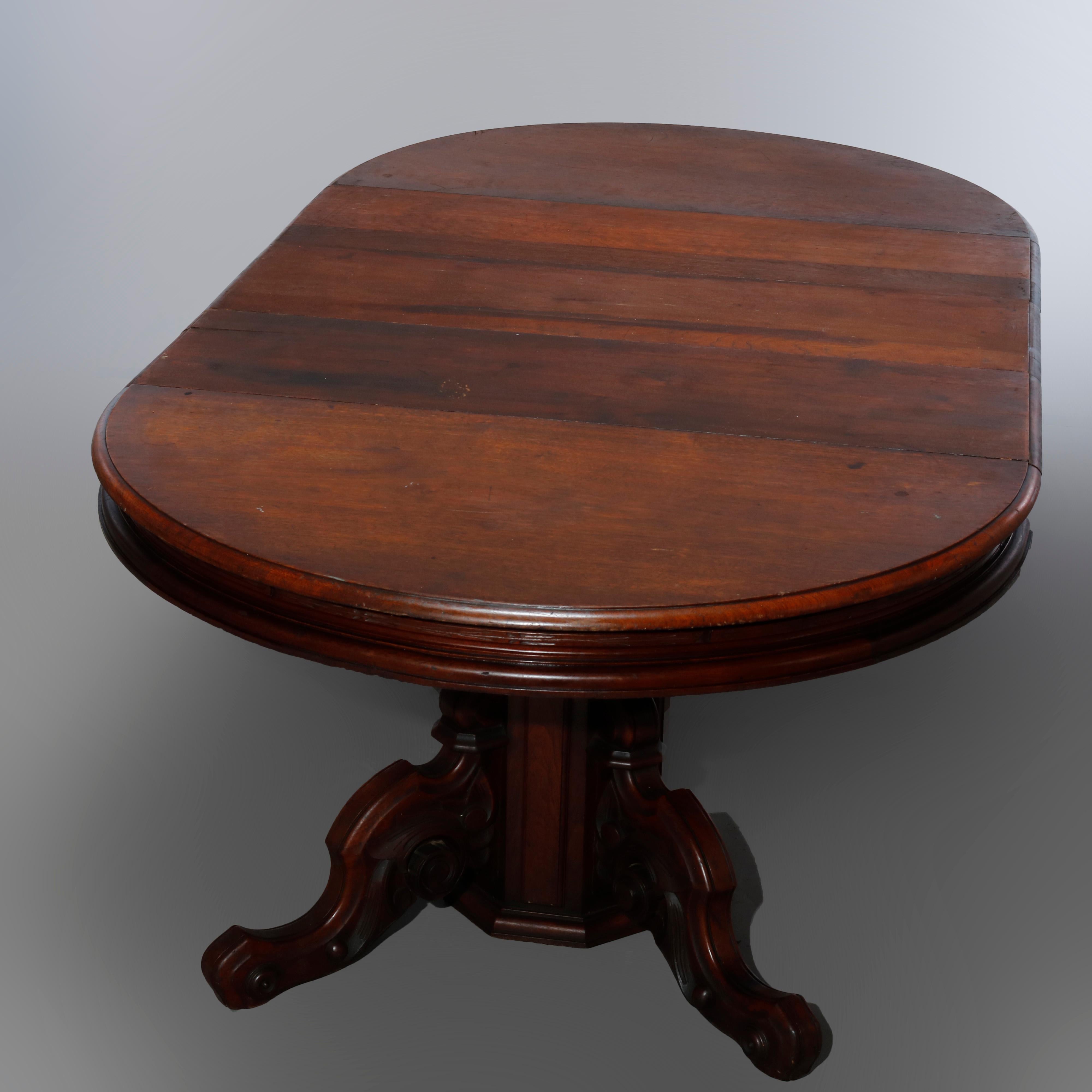An antique Renaissance Revival extension dining table offers walnut construction with round top over split pedestal base raised on four carved legs having scroll feet, extends and accepts two leaves, c1880

Measures: 28.25