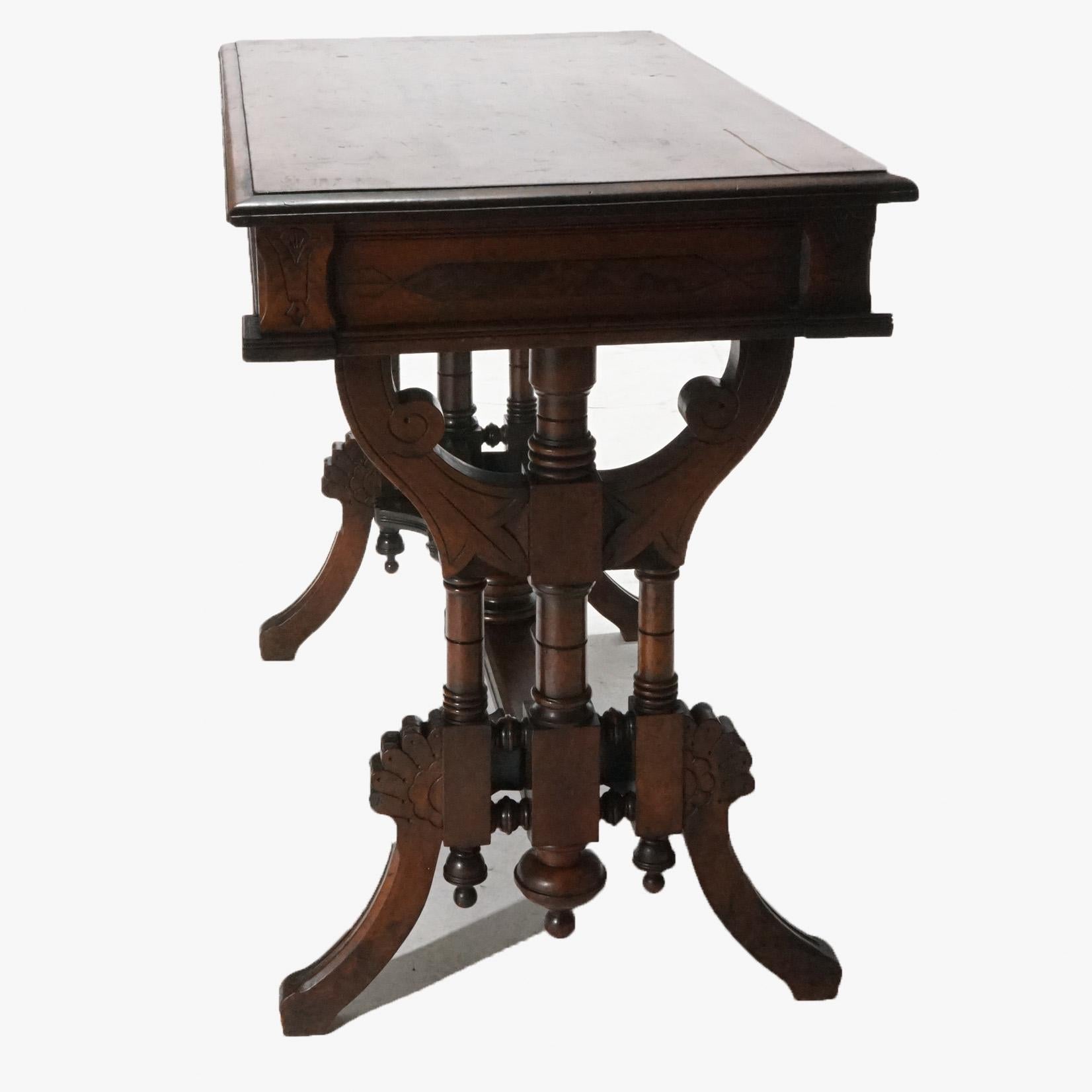 An antique Renaissance Revival library table offers walnut construction with beveled top having carved and incised skirt raised on ornate trestle legs having turned columns and decorated stretcher with central finial, c1890.

Measures- 30''H x 36''W