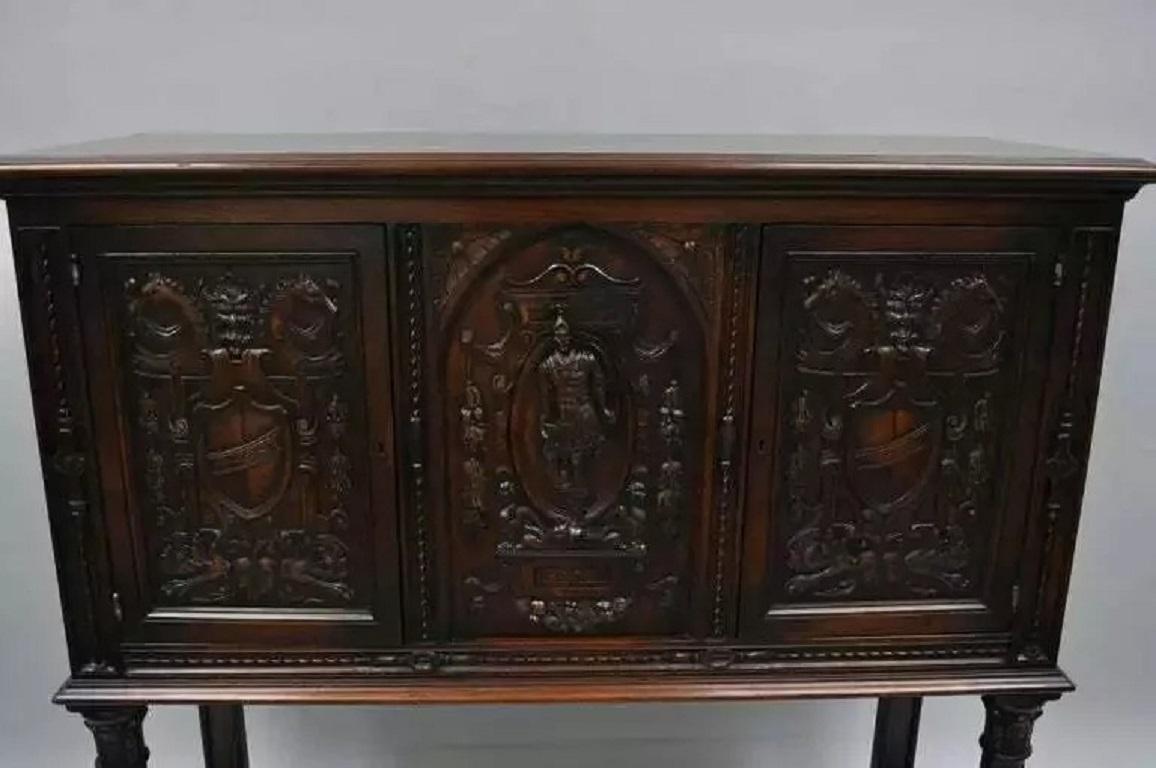 Antique Renaissance Revival Figural Carved Walnut Cabinet Sideboard Cupboard. Item features ornately carved walnut panels of shields and crests, horse heads, as well a central soldier. Cabinet has two swing doors, carved support columns, lower