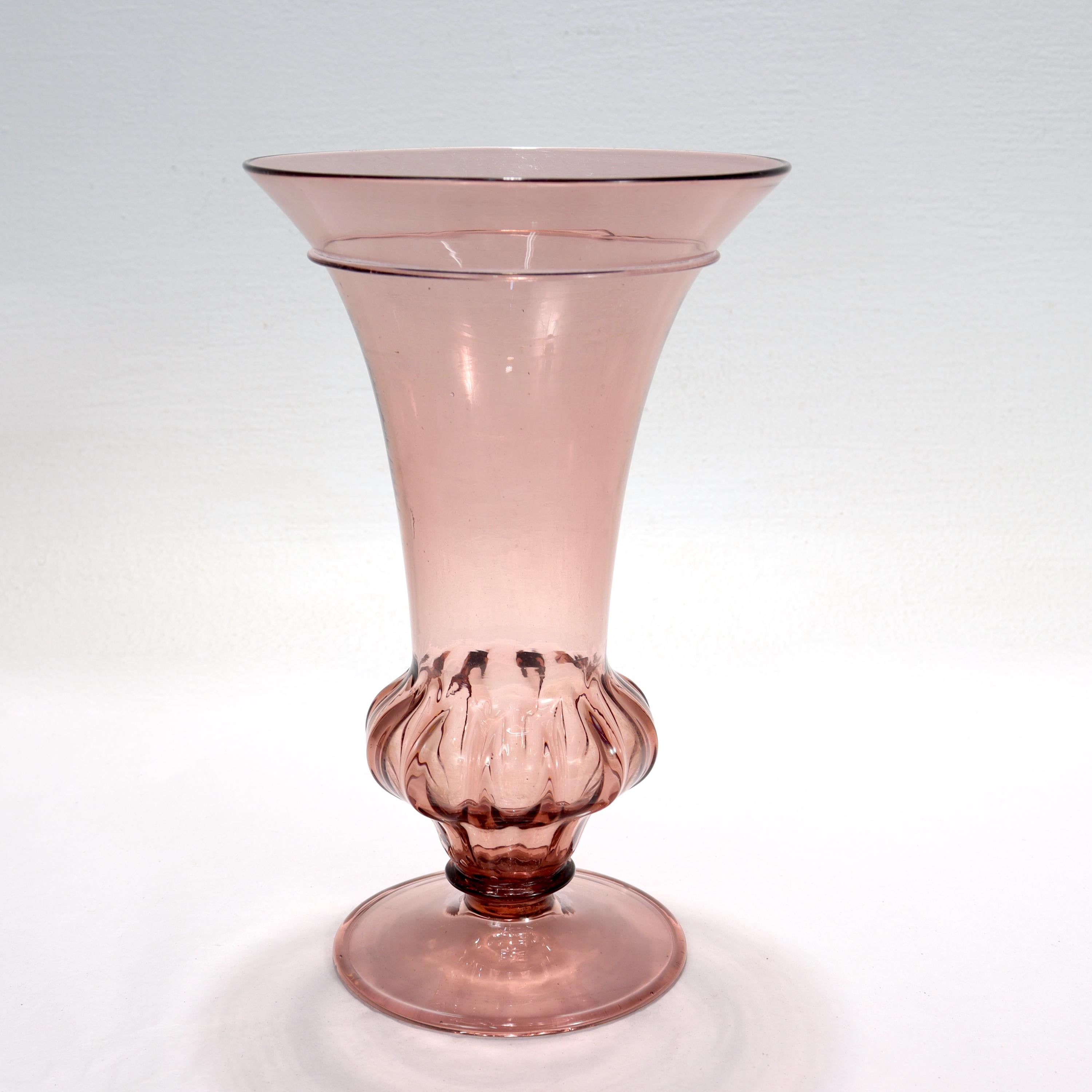 Vase en verre vénitien ou de Murano de couleur pourpre.

Le sommet en forme de trompette est surmonté à la base d'un bouton cannelé et supprimé, et repose sur un pied en forme de disque. 

Marque de pontil grossière sur la face