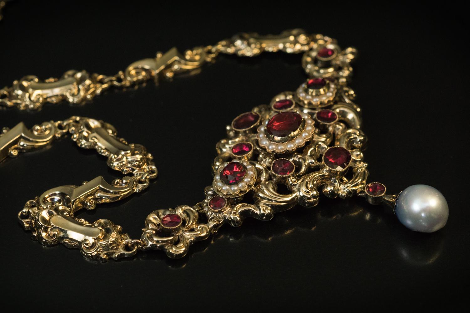Circa 1880

This striking 19th century hollow gold necklace is designed in the Renaissance style of the 1500s – early 1600s. The necklace is crafted in 14K gold and embellished with garnets and pearls. The semi-baroque shape pearl measures 10 x 9.48
