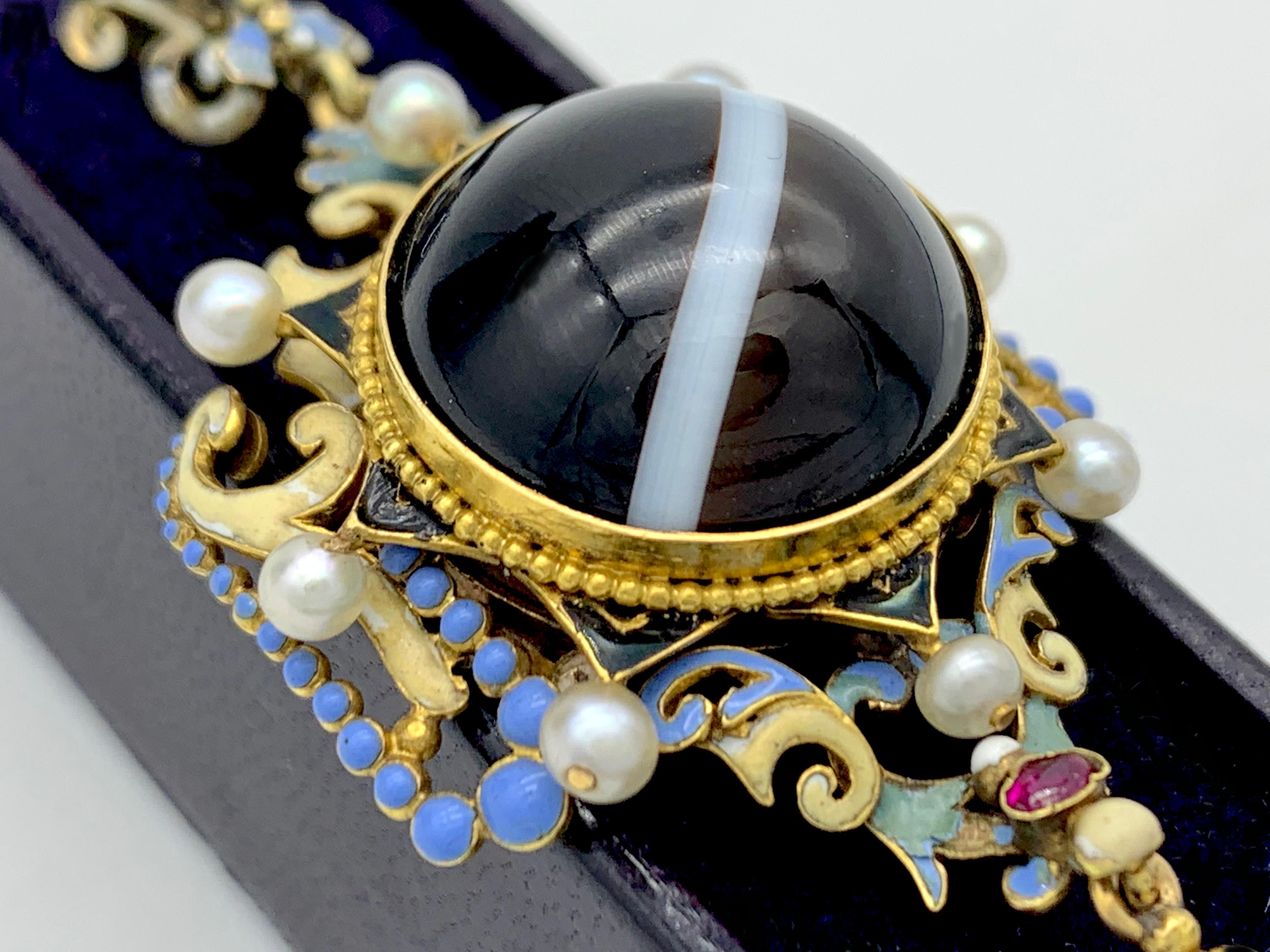 This wonderful holbeinesque renaissance revival pendant is set with a lovely sardonyx cabochon and richly decorated with polychrome enamel, rubies and fine natural pearls. There ia locket on the reverse.
This bright and lively jewel has been,