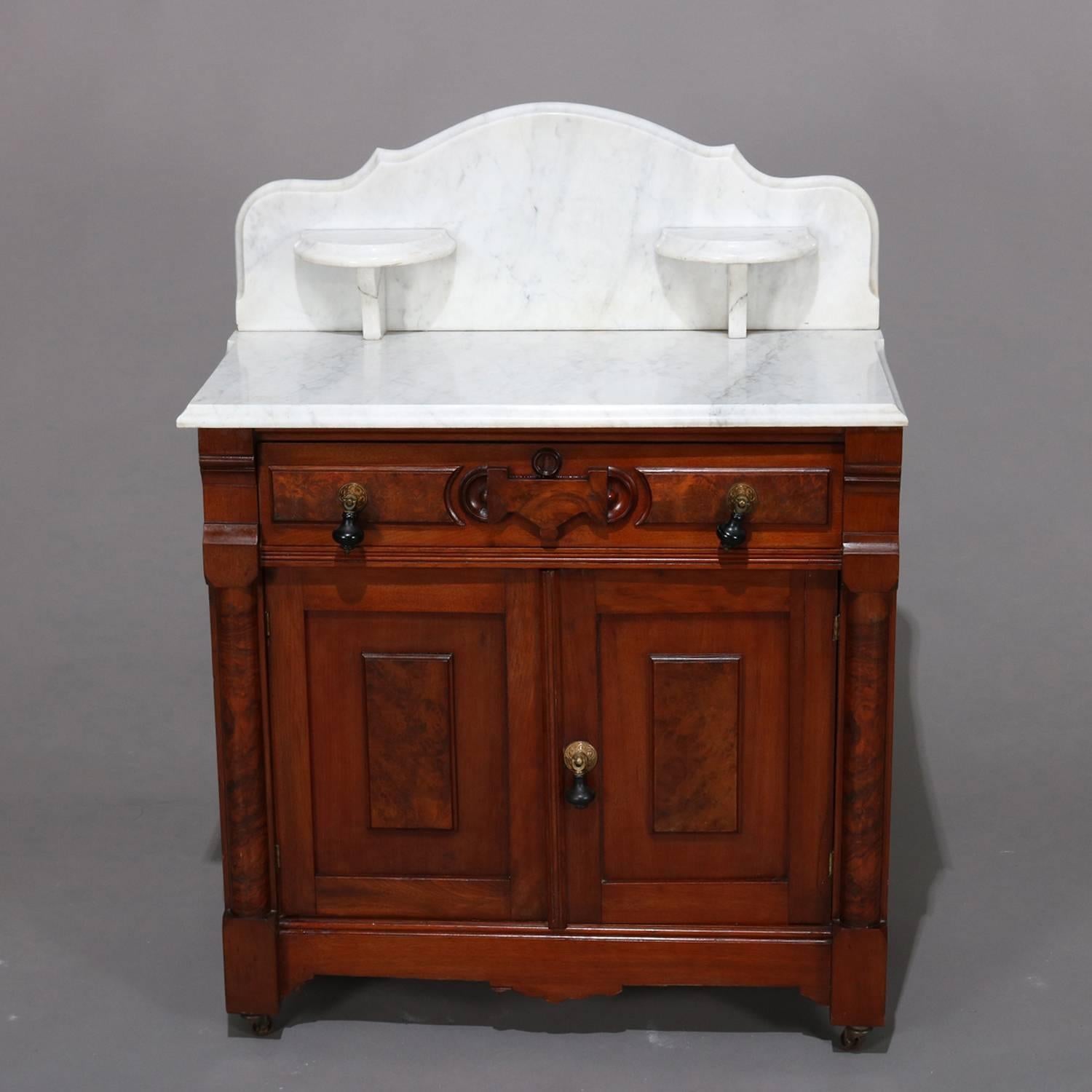 Antique Renaissance Revival carved walnut washstand features scalloped and bevelled marble backsplash having candle stands over marble top cabinet with burl having frieze drawer over lower double door cabinet, 1870.

Measures: 39.5