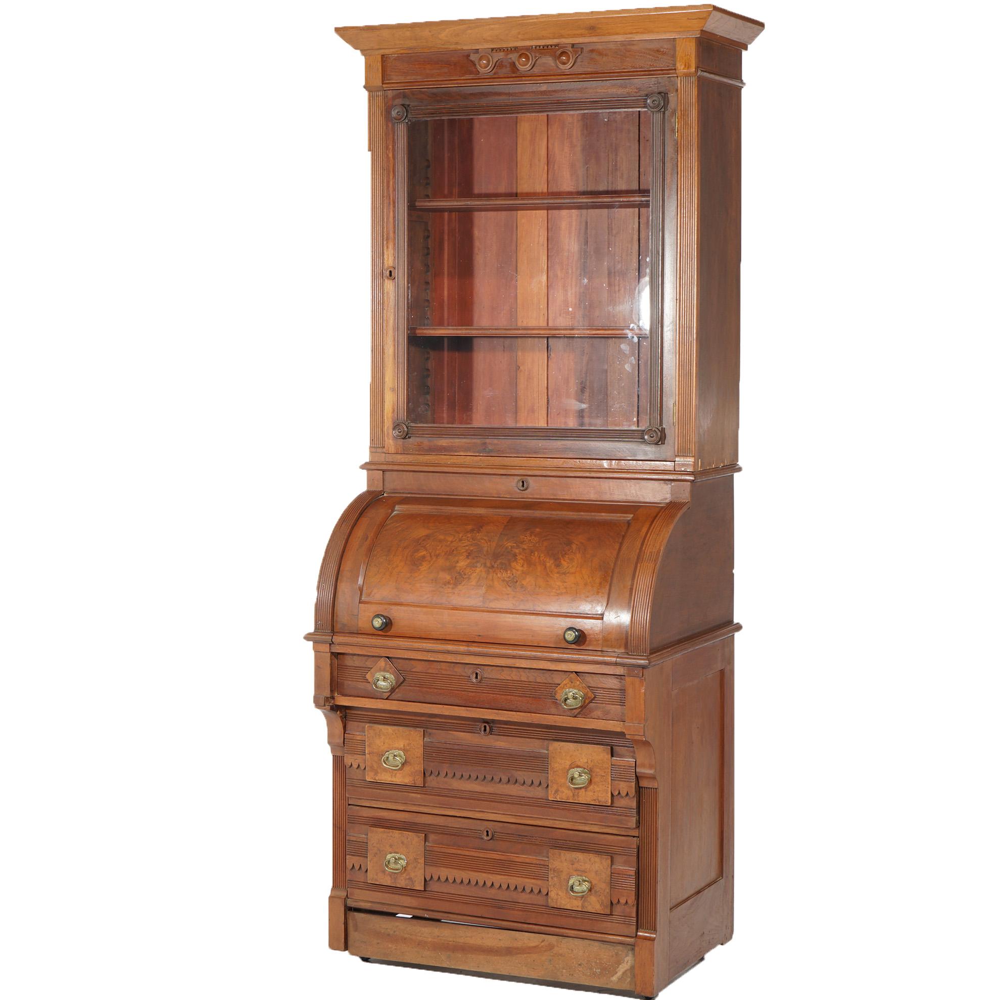 An antique Renaissance Revival secretary offers walnut and burl construction having upper bookcase with single glass door opening to shelved interior over barrel roll top desk with lower drawers, c1890

Measures - 83
