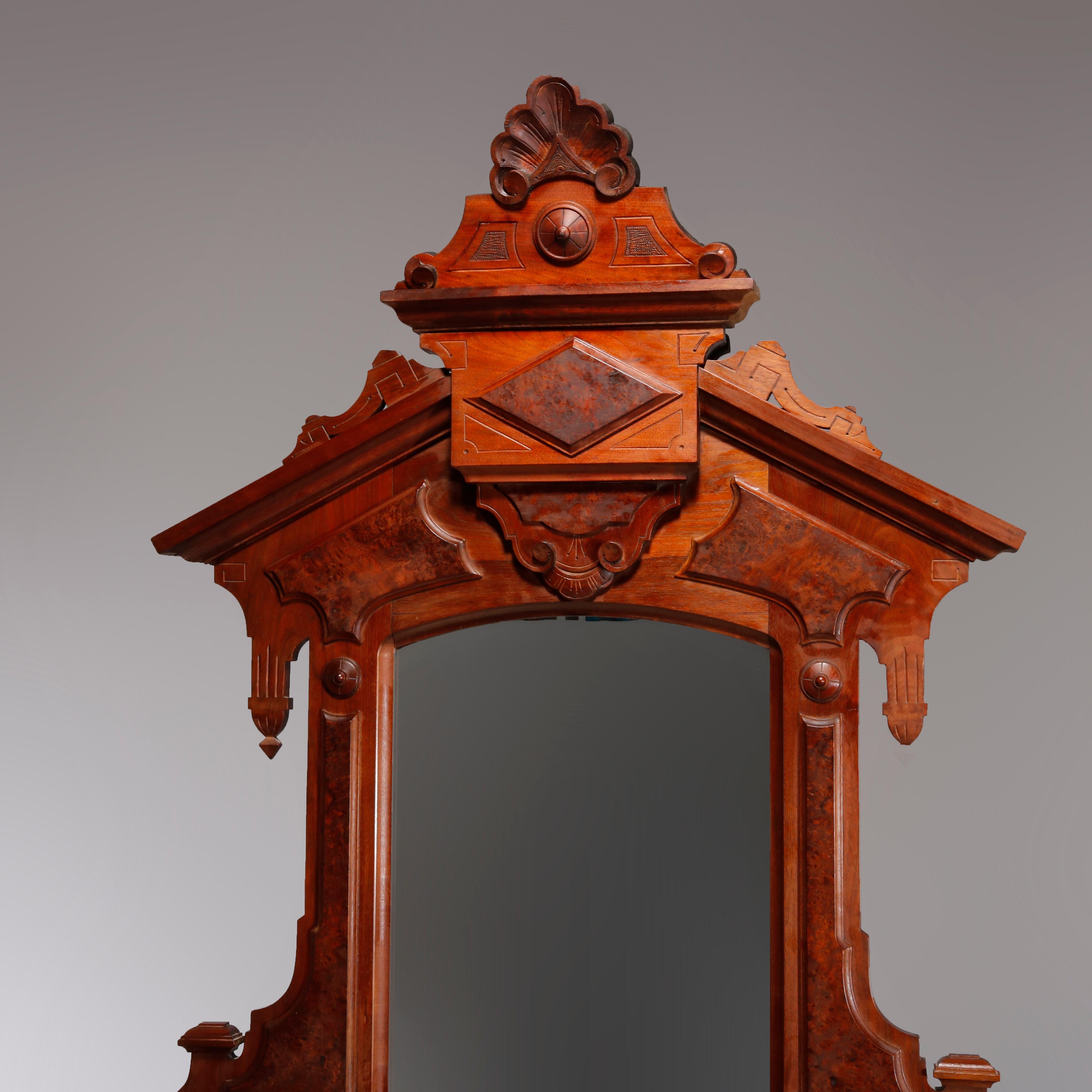 An antique Renaissance Revival dresser offers walnut construction with mirror frame having carved crest with central shell, flanking geometric and incised elements, drop finials, applied burl panels and candle stands surmounting drop center chest of