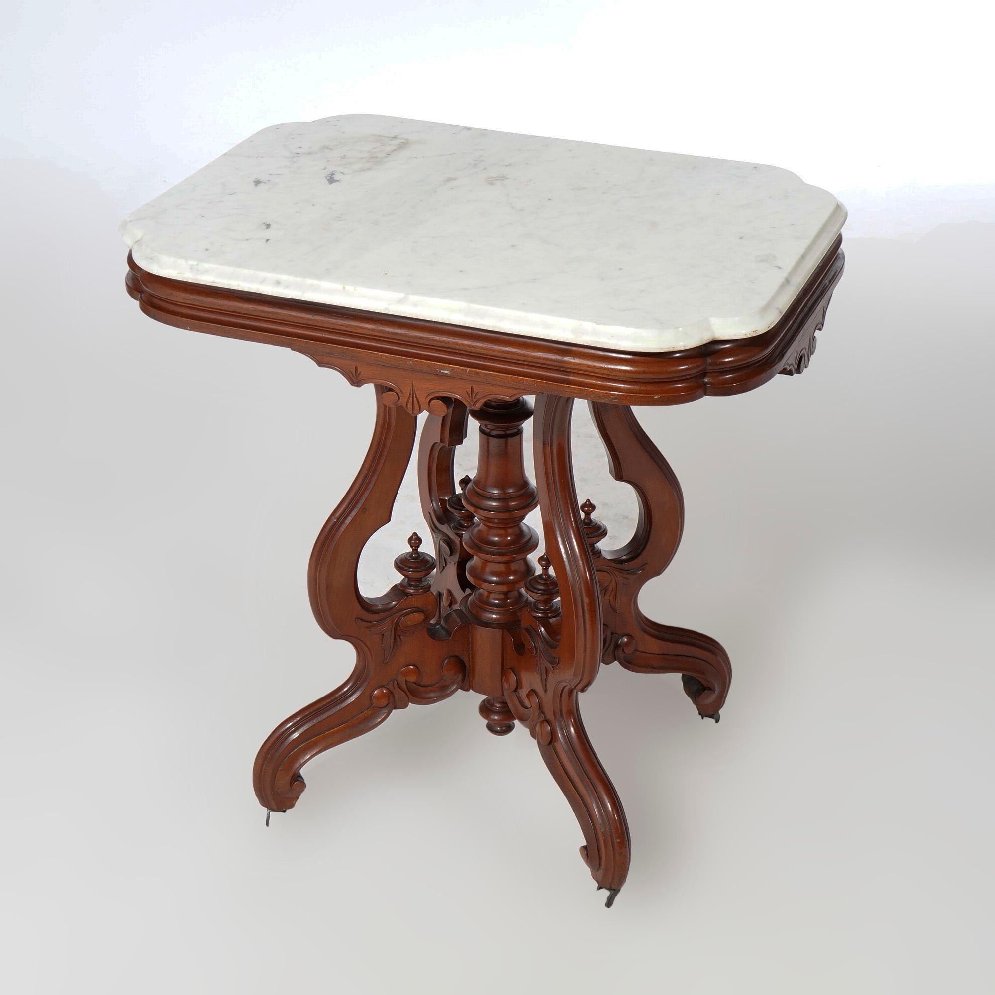 An antique Renaissance Revival parlor center table offers beveled shaped marble top over carved walnut base having shaped skirt, incised decoration, foliate elements and raised on scroll form cabriole legs with central turned column,