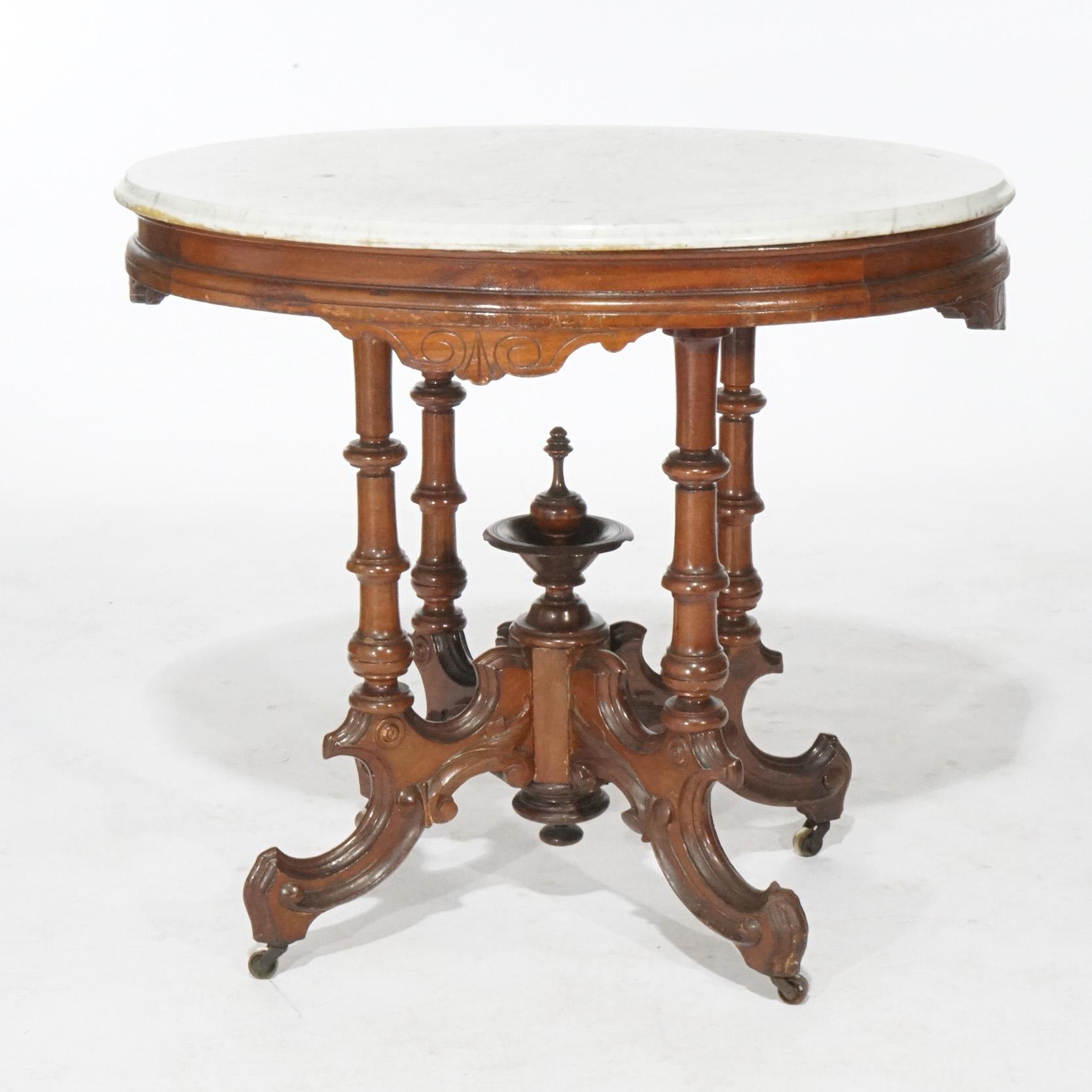 An antique Renaissance Revival parlor center table offers beveled oval marble top over walnut base having scroll incised shaped skirt, four banded column supports with a central urn form turned finial, circa 1890

Measures- 30''H x 33.75''W x