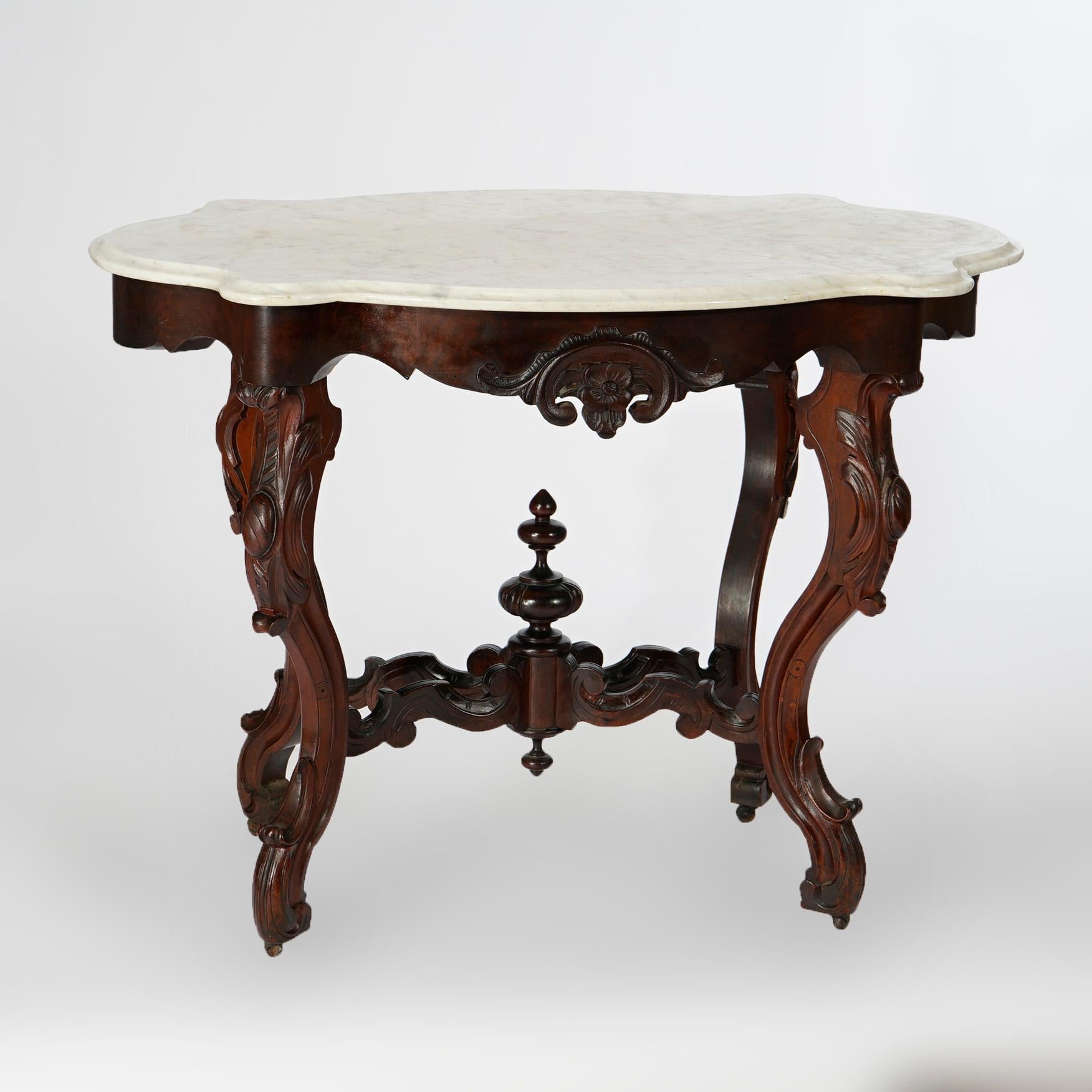 An antique Renaissance Revival parlor table offers shaped and beveled marble turtle top over carved walnut and rosewood base having shaped skirt with floral and foliate elements, raised on decorated cabriole legs with scroll form stretcher having