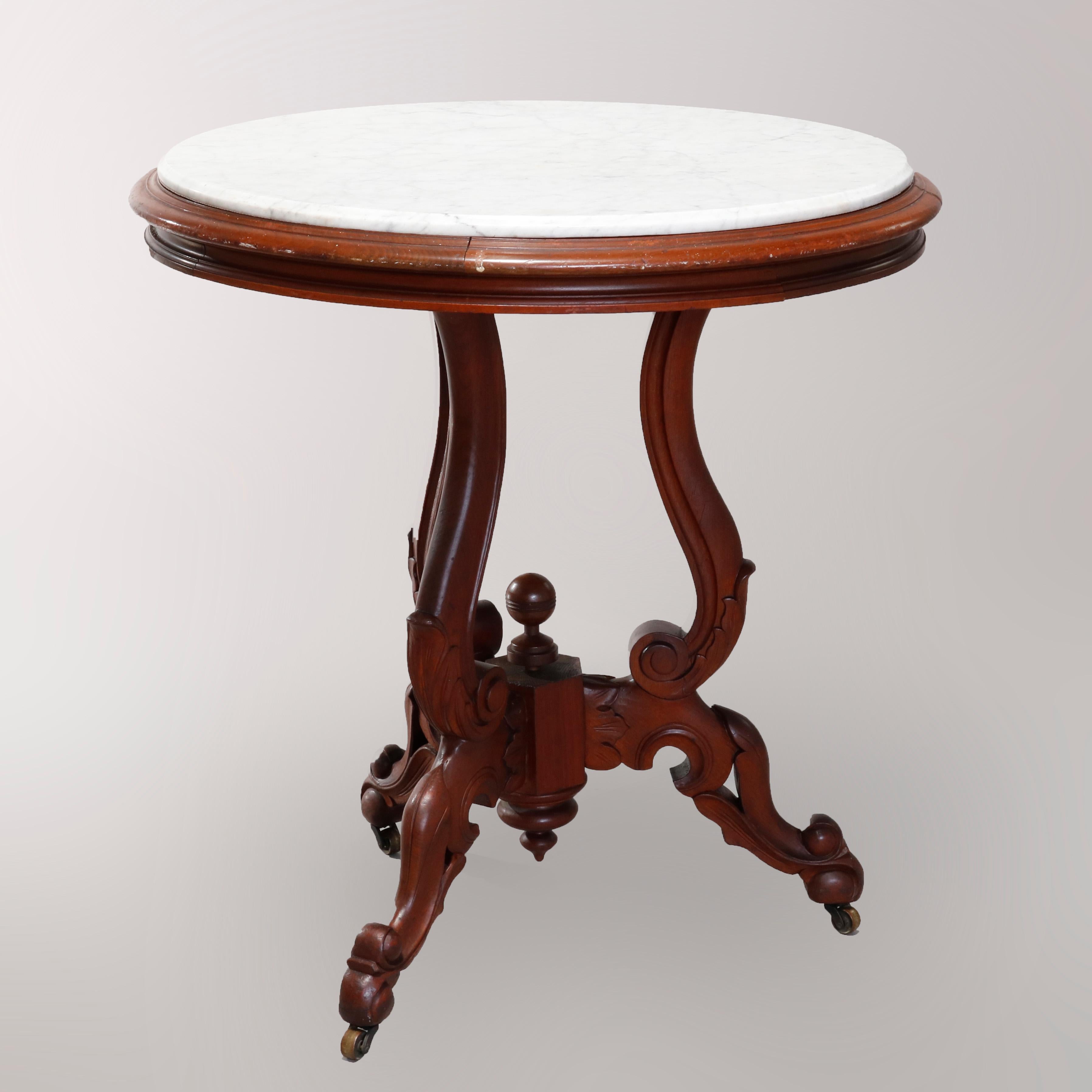 An antique Renaissance Revival center table offers round form with beveled marble top surmounting carved walnut base with three scroll form supports terminating in central drop and raised finials, raised on carved acanthus cabriole legs with