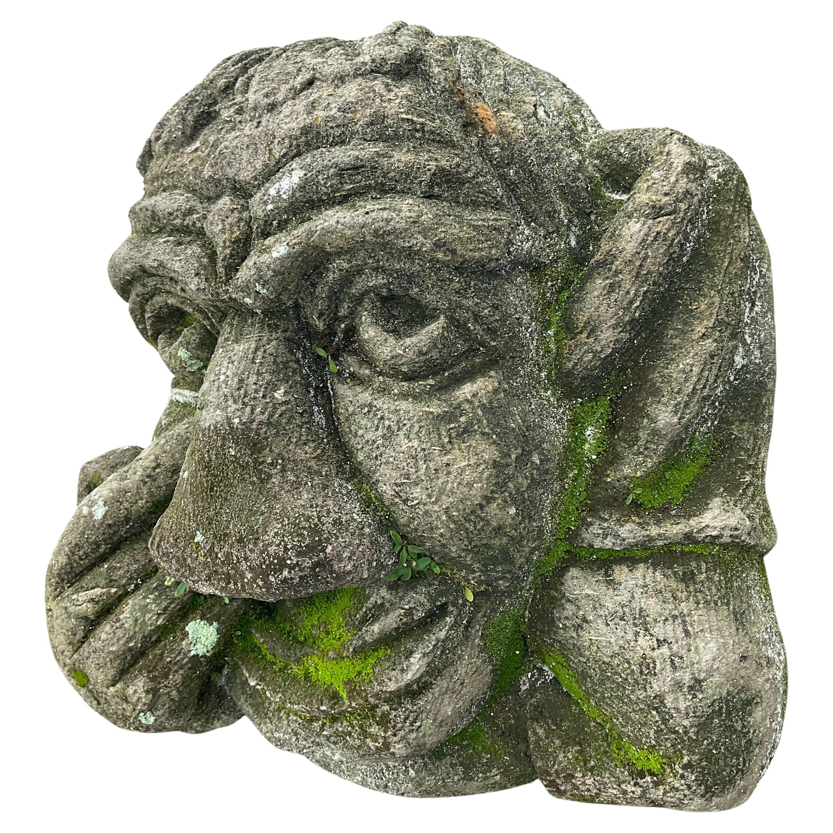 Stone head of a grotesque mounted on later cast iron stand. Statue has strong detailed facial features with one hand touching right eye. Wonderful old patina. Would look unique and charming in any garden. Possibly a fountain head.