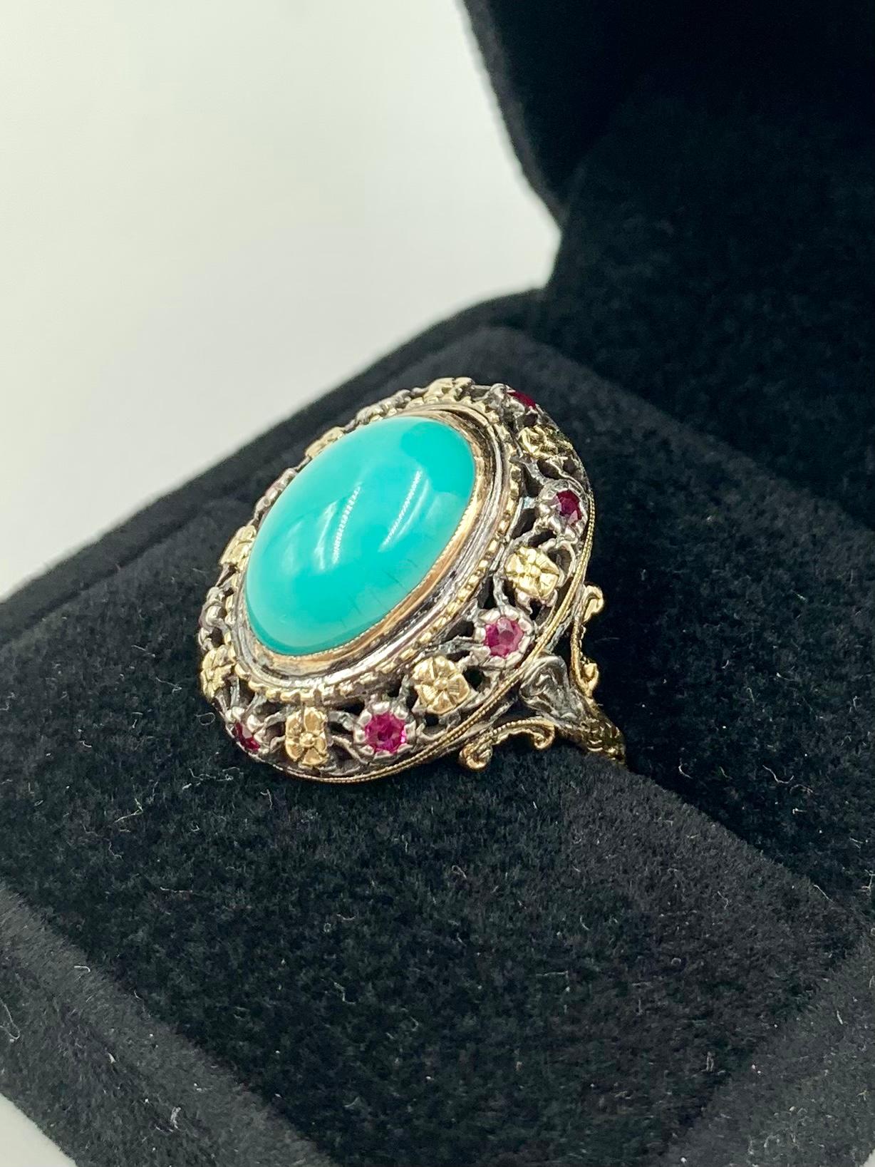 Beautiful antique Renaissance style 18K gold ring featuring a fine large oval natural Persian cabochon turquoise gem exquisitely set in a floral filigree setting composed of eight yellow gold flowers and eight white gold flowers with ruby centers.