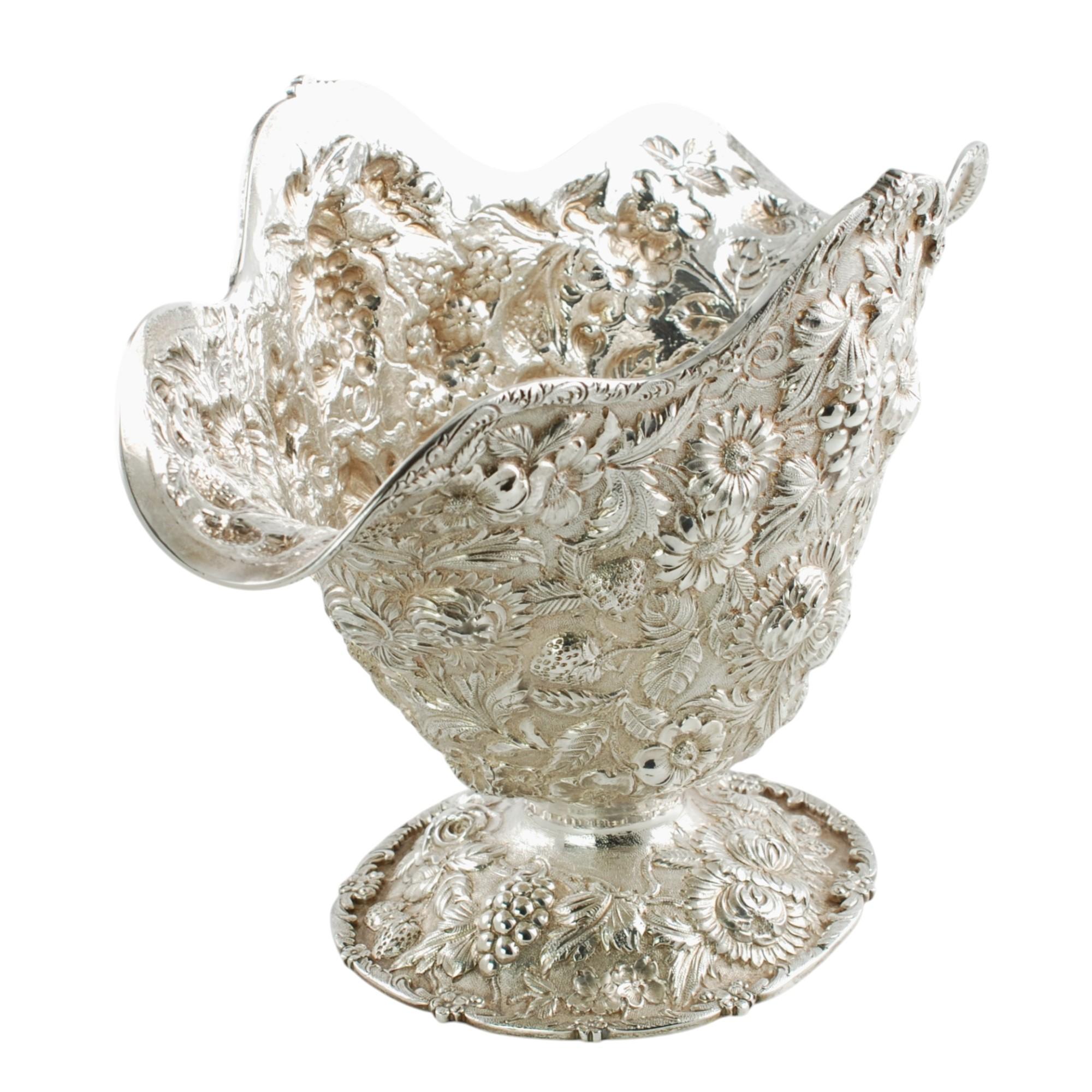 Diese exquisite Schale mit Fuß aus Sterlingsilber von Loring Andrews aus dem frühen 20. Jahrhundert weist ein handziseliertes Repoussé-Dekor auf, das aus zahlreichen Blumen, Erdbeeren und Trauben sowie Blättern und geschwungenen Ranken besteht, die