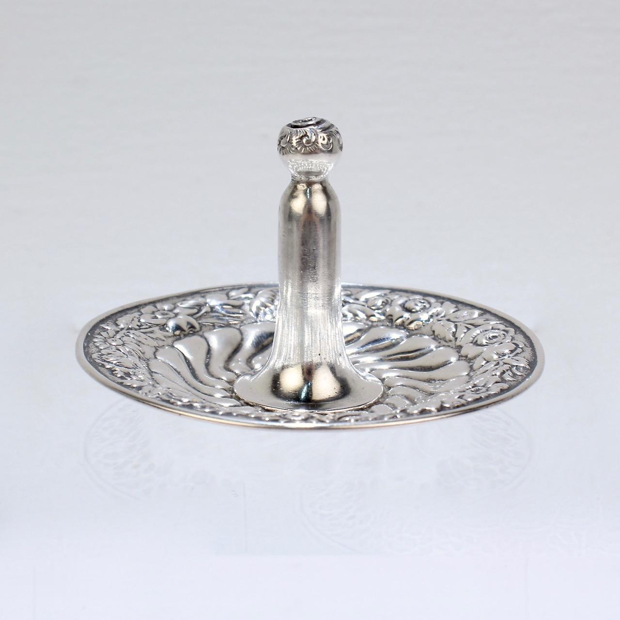 A fine, antique American sterling silver ring stand. 

With floral repousse decoration to the edge and finial and fluted decoration to the base. A streamlined variant of a 'ring tree', this ring stand has one central stand -- singular and