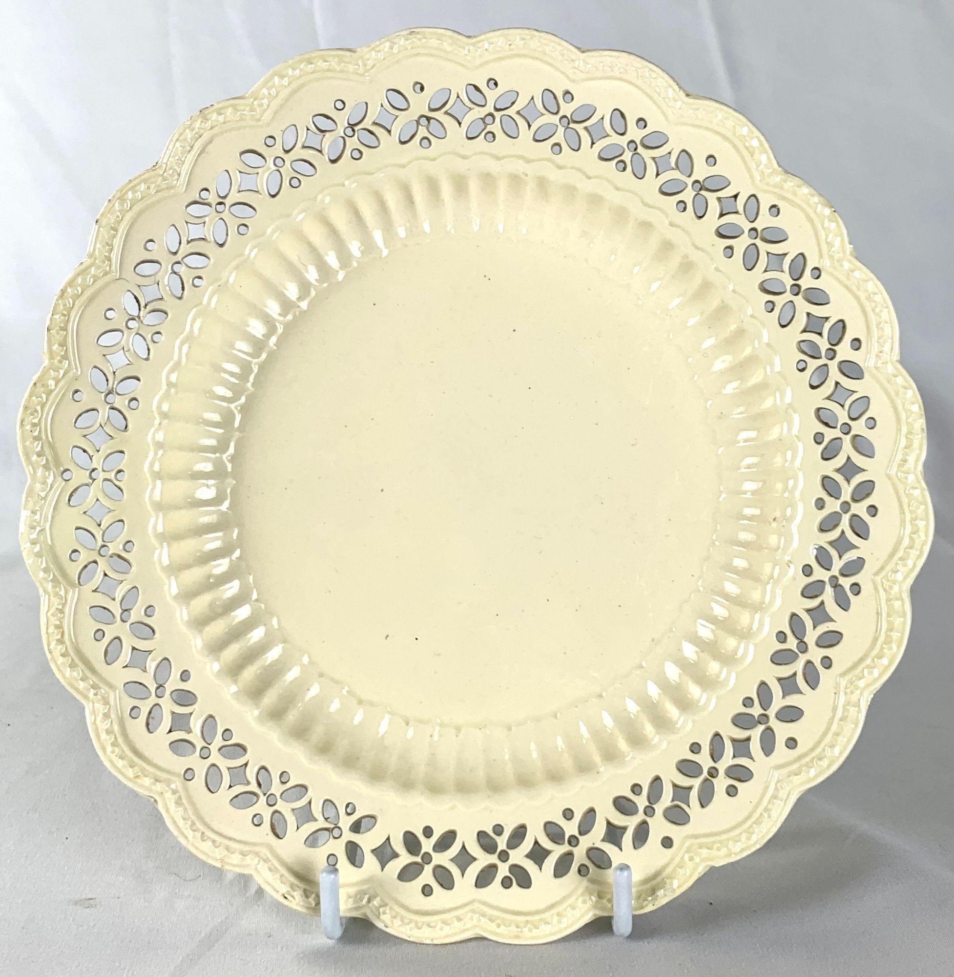 Cette petite assiette anglaise réticulée en creamware du XVIIIe siècle est à la fois élégante et magnifiquement travaillée.
Fabriquée en Angleterre vers 1780, l'assiette présente une délicate bordure ajourée dans un motif de diamants et de points,