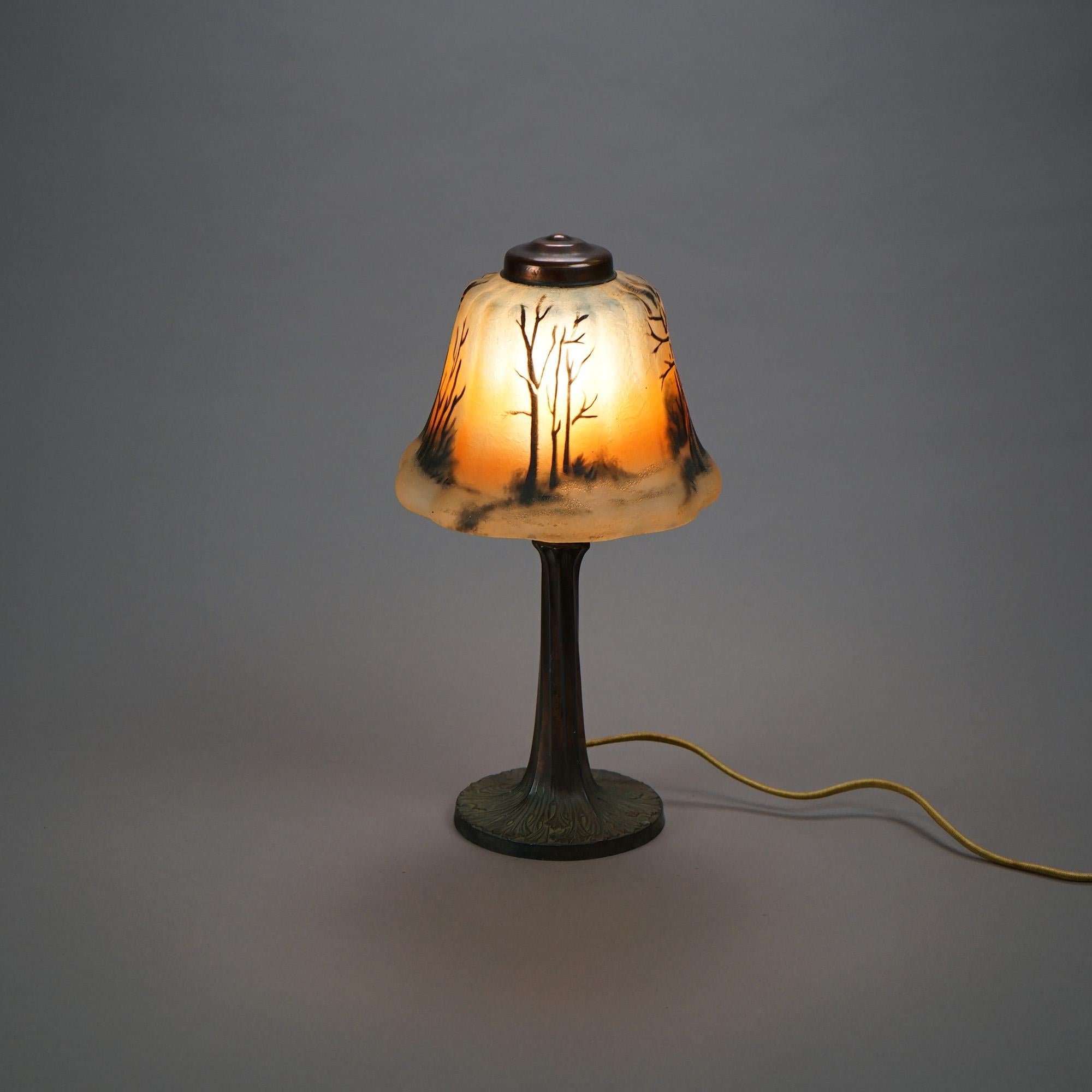 An antique boudoir table lamp offers reverse painted glass shade with landscape scene over single socket cast metal base, c1920

Measures- 13.75''H x 7''W x 7''D.