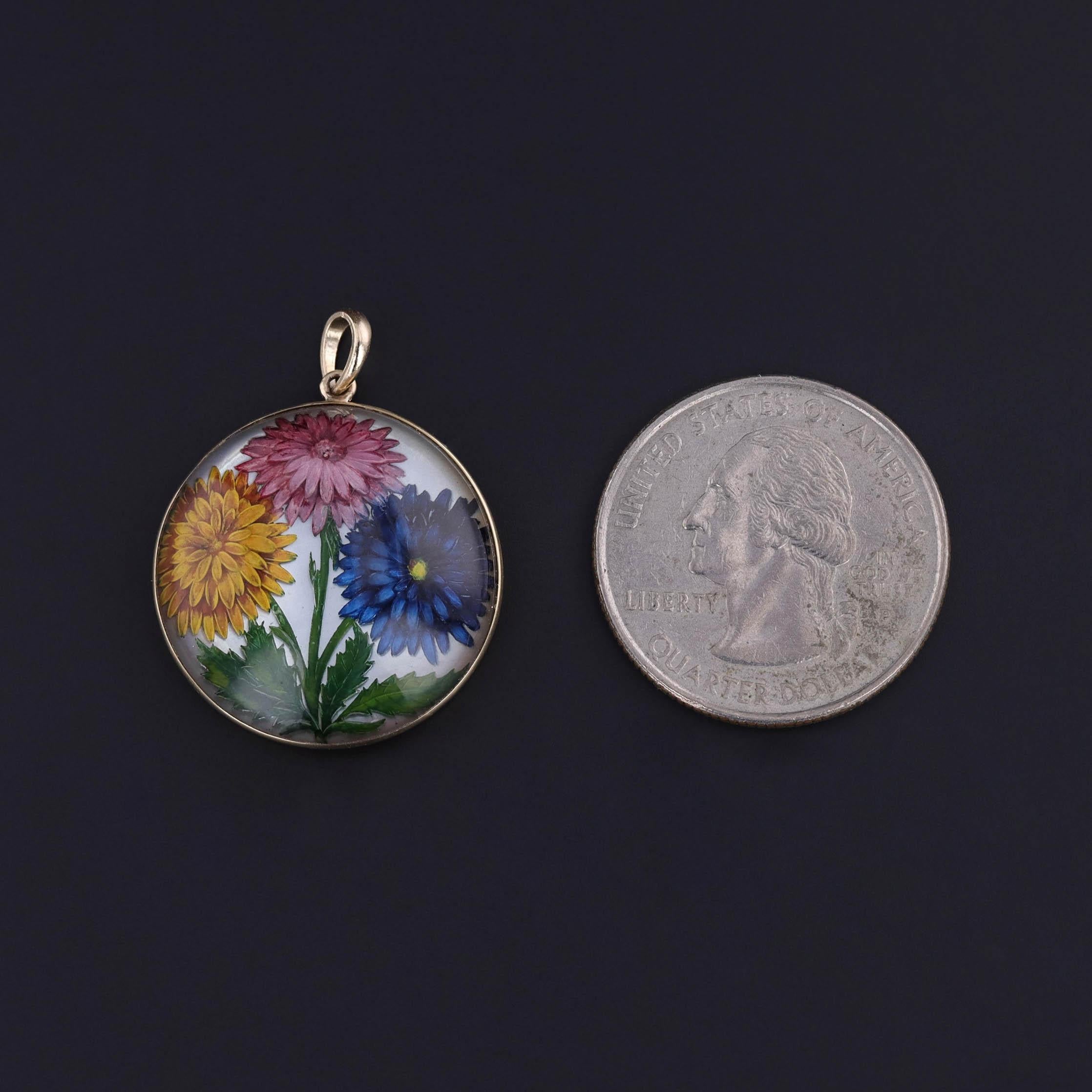 Délicate célébration de l'art botanique, ce pendentif ancien converti (vers 1900) présente un cristal de roche finement peint à l'envers - une technique également connue sous le nom de cristal d'Essex - représentant trois chrysanthèmes vibrants dans