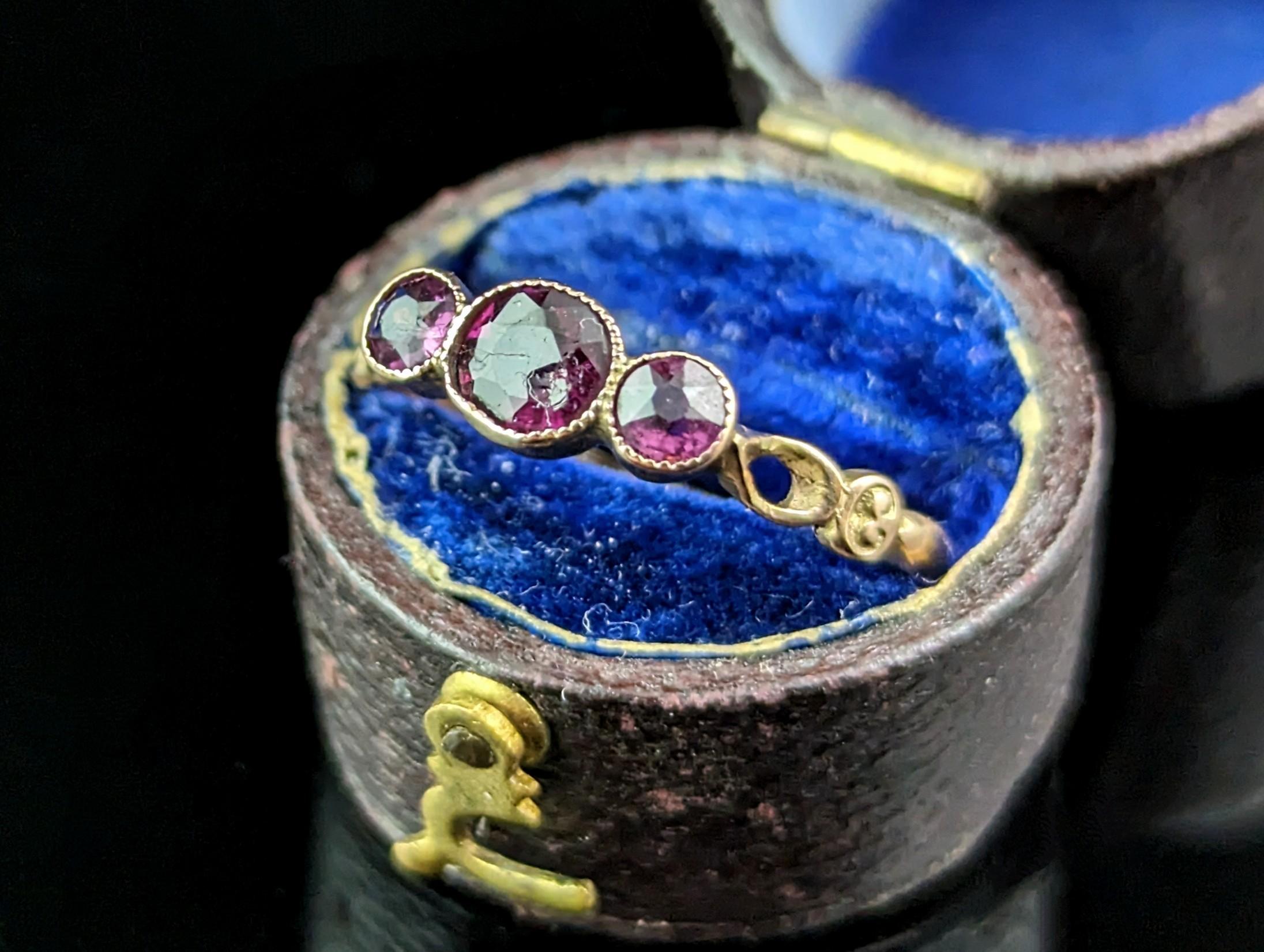 A pretty and dainty little antique Rhodolite Garnet three stone ring.

This is a sweet and delicate piece with a slender 9ct rose gold band and decorative scrollwork and cut out shoulders.

The face is bezel set with three Rhodolite Garnets the