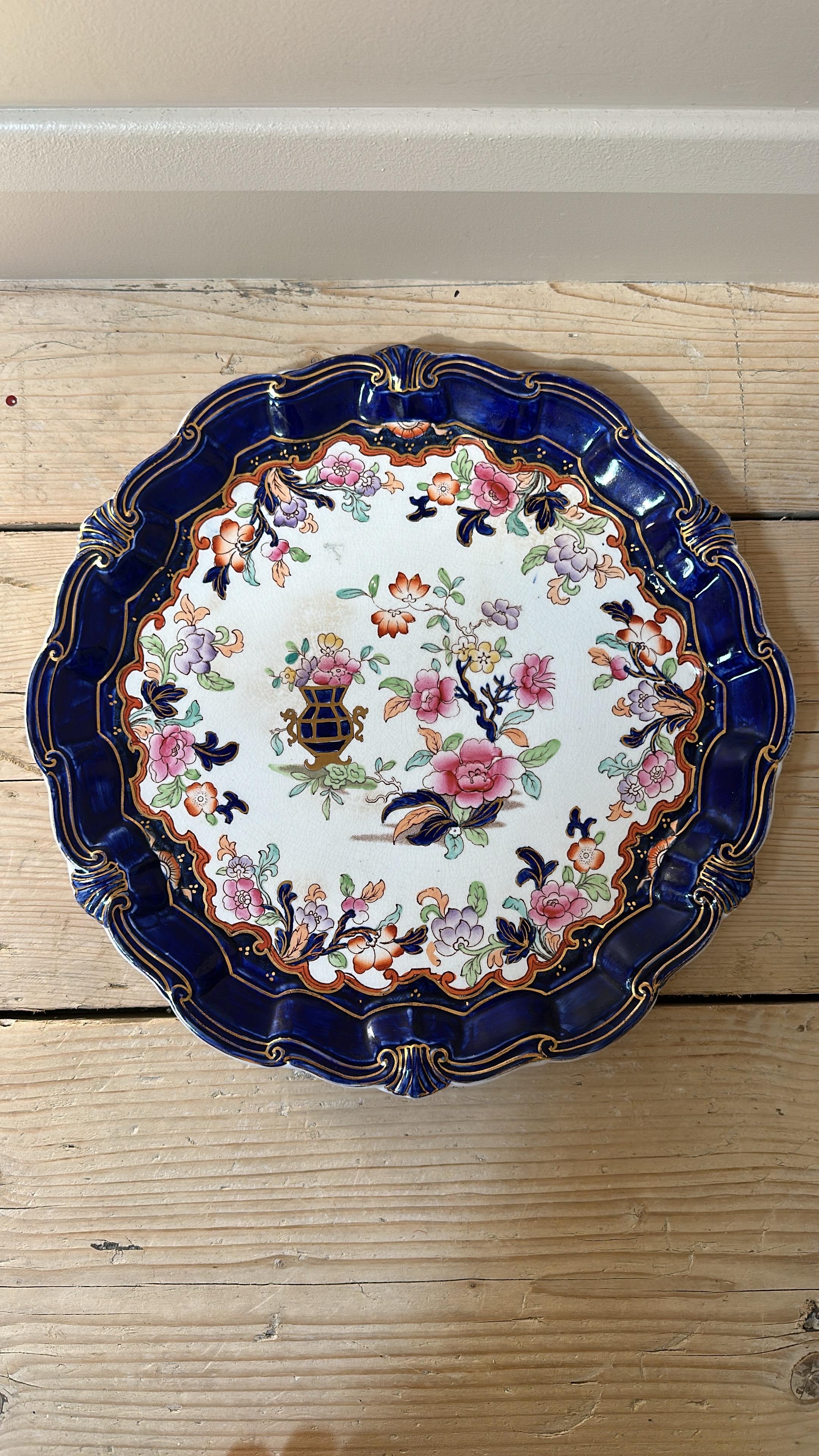 Cette grande assiette décorative est un exemple classique de la poterie Ridgway ancienne, présentant la palette de couleurs vibrantes de style Imari et les détails complexes qui ont fait la renommée des potiers du Staffordshire au début des années
