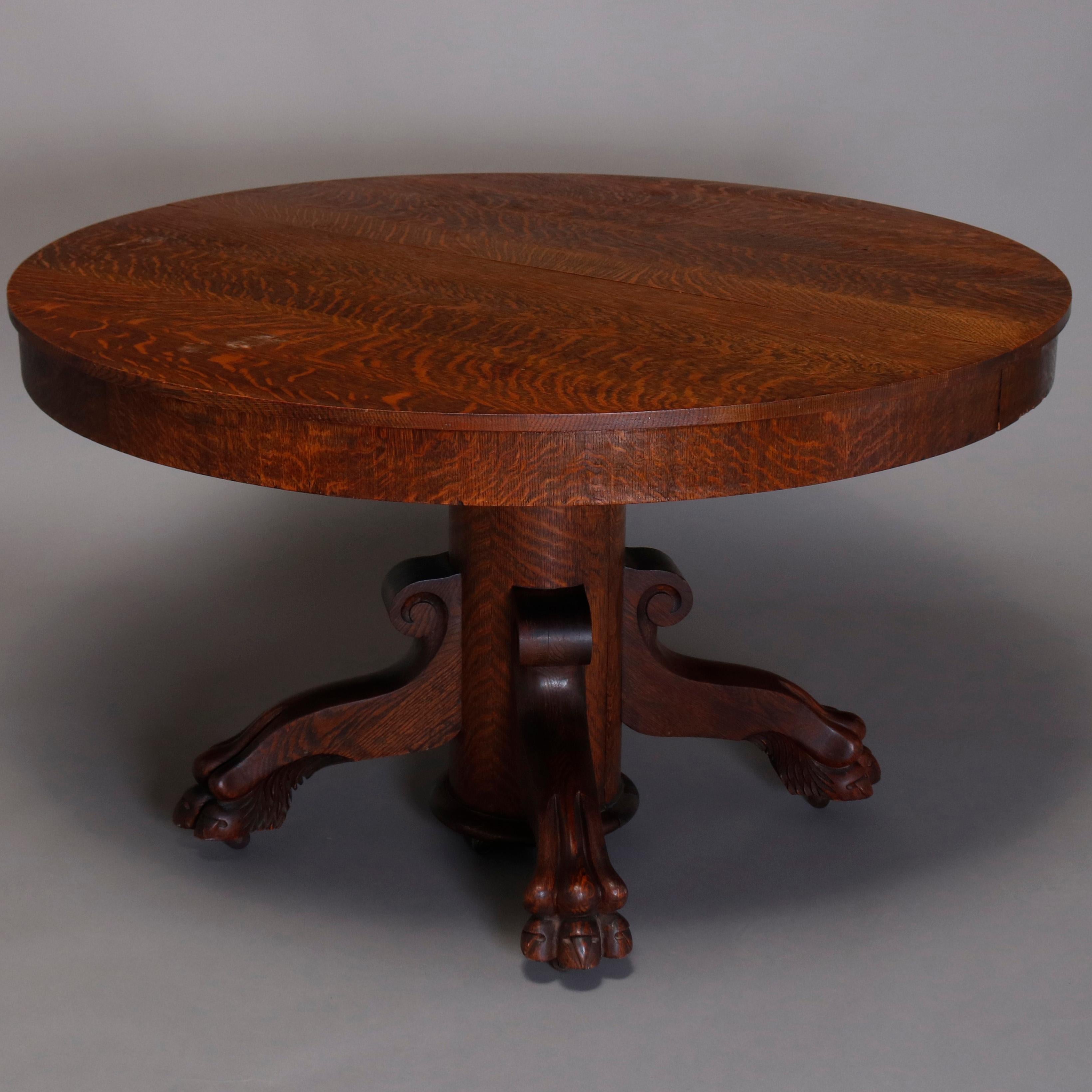 An antique R.J. Horner style dining table offers original finish and solid quarter sawn oak round skirted top surmounting split pedestal raised on four legs with scroll form capitals and terminating in carved paw feet, extends to oval with one 12.5