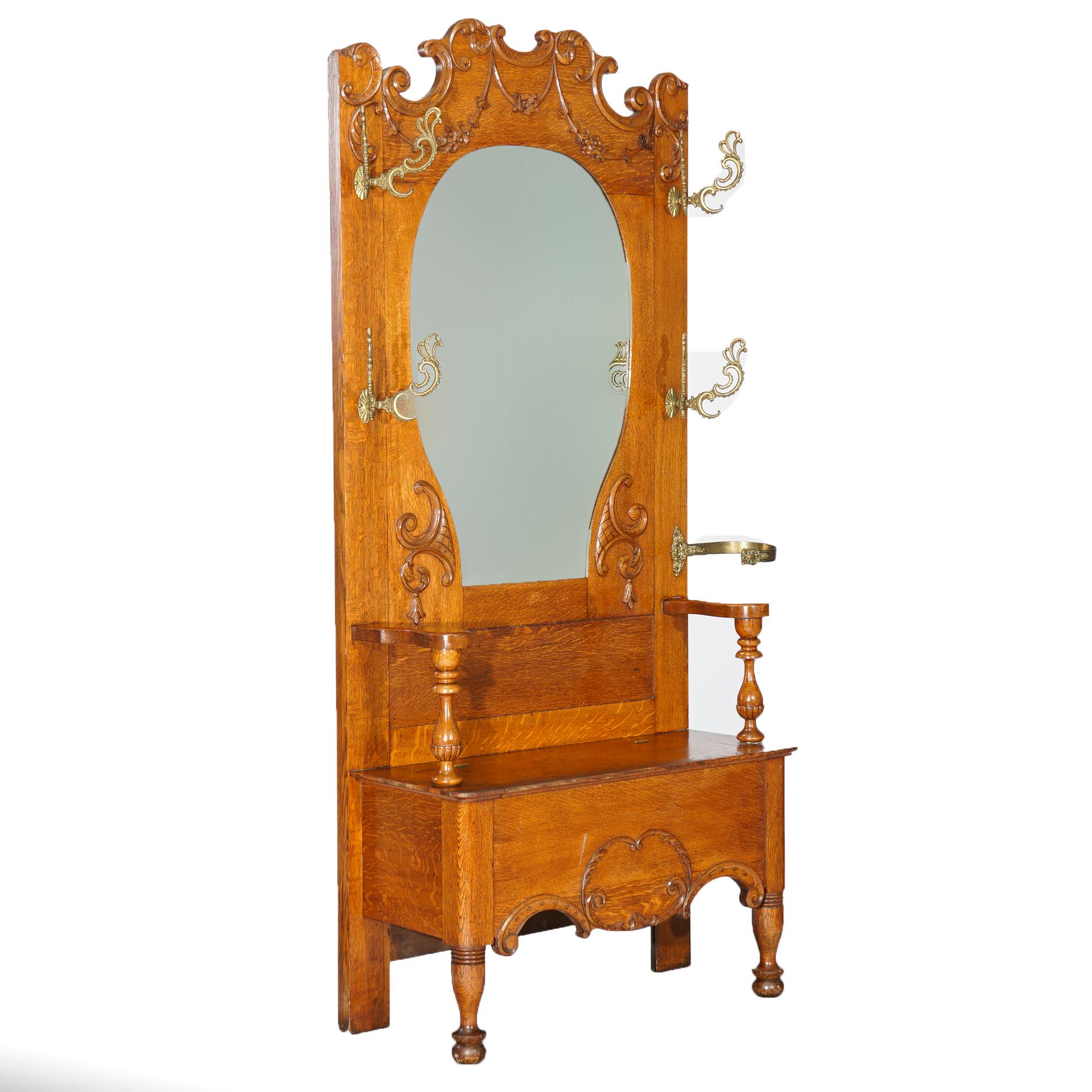 An antique hall seat attributed to RJ Horner offers golden oak construction with shaped crest having carved scroll and foliate elements over beveled mirror in horse show form, seat with lift top, c1900.

Measures - 79.5''H x 44.25''W x 15.5''D; 21''