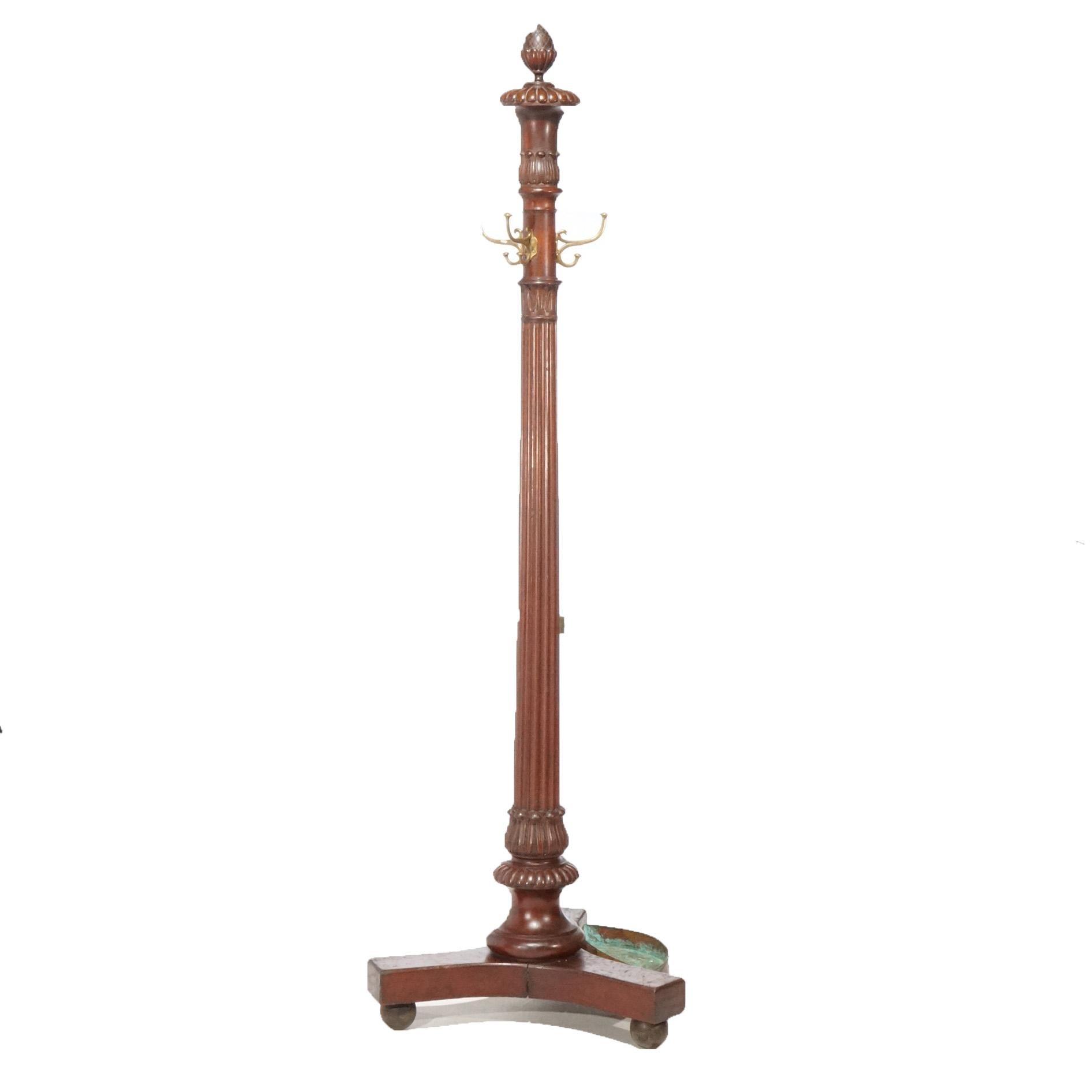 An antique hat rack in the manner of RJ Horner offers mahogany construction with carved foliate elements, reeded column, and tripod footed base with umbrella drop tray, circa 1900

Measures- 77.5''H x 24.75''W x 24.75''D.