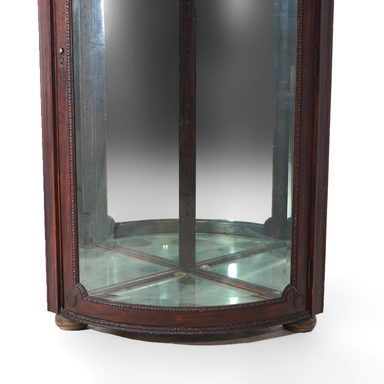 ***Ask About Reduced In-House Shipping Rates - Reliable Service & Fully Insured***

An antique corner china cabinet display case in the manner of RJ Horner offers oak construction with foliate carved crest over cabinet having single curved glass