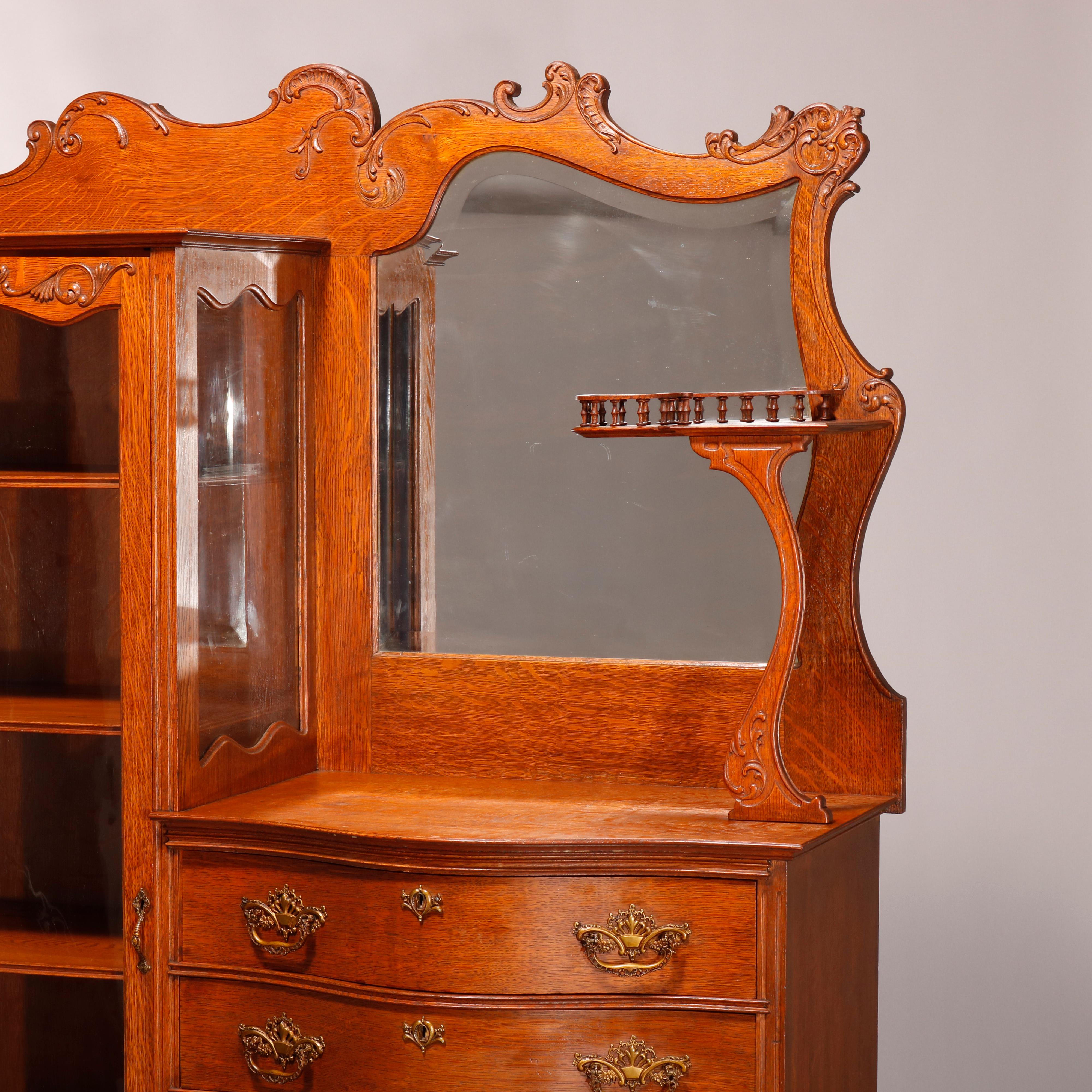 An antique china buffet in the manner of RJ Horner by Rockford Standard Furniture Co., Rockford, Illinois offers oak construction with foliate and scroll carved crest surmounting side-by-side with shelved single door vitrine aside server having