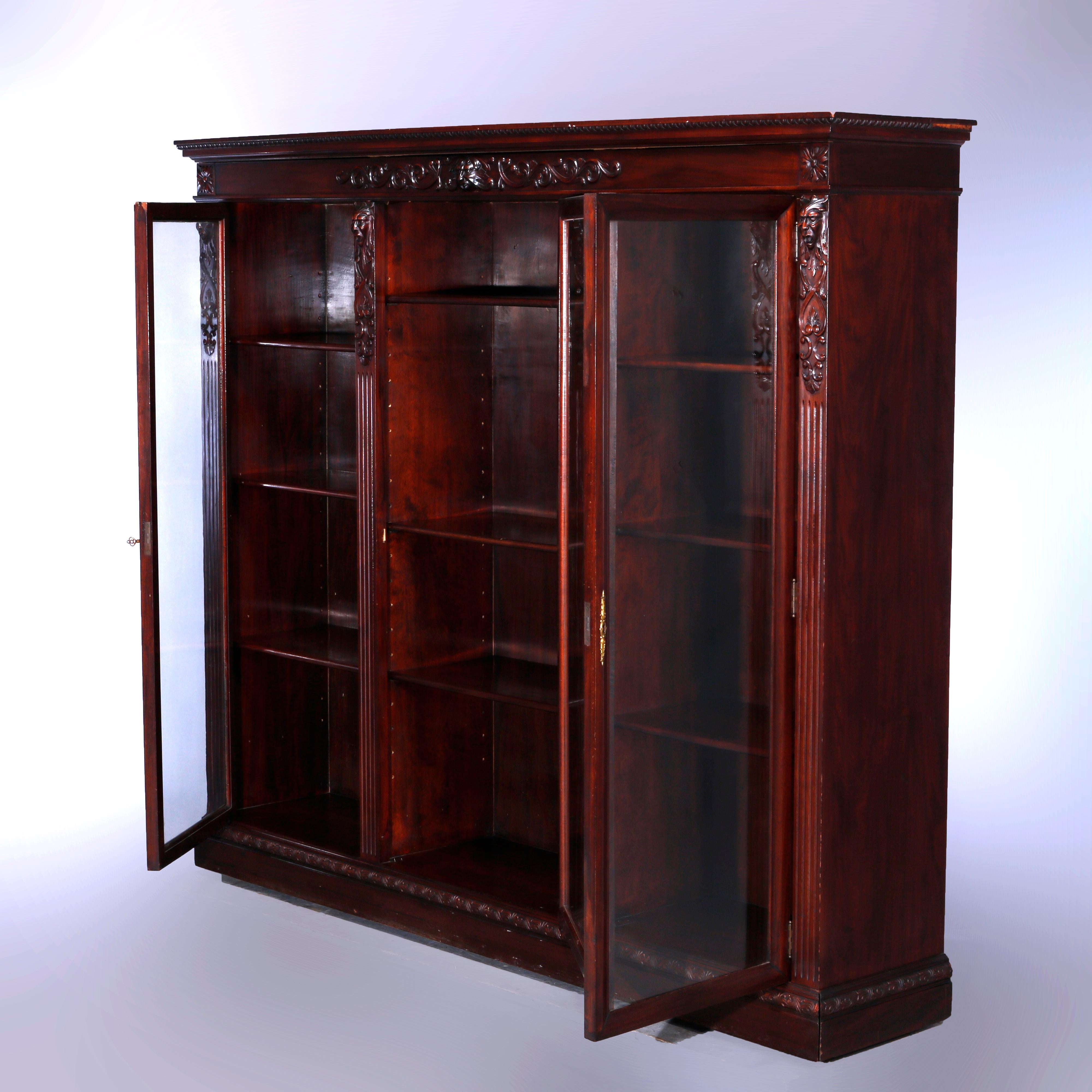 An antique bookcase in the manner of RJ Horner offers mahogany construction with figural carved lion, satyr and foliate elements, triple glass doors opening to shelved and divided interior, c1890

Measures - 63.5'' H x 73.25'' W x 14.75'' D.