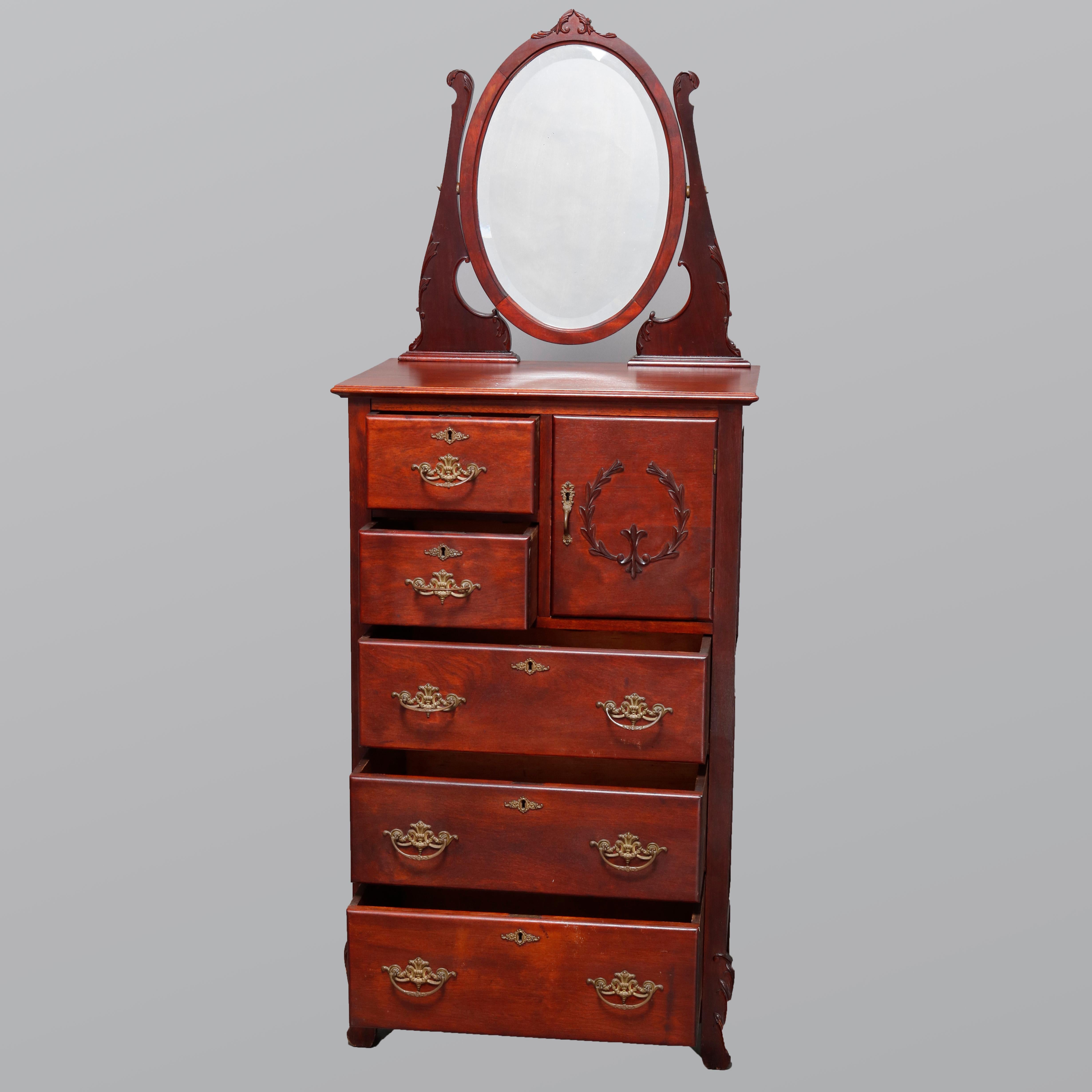 An antique R.J. Horner School lingerie chest offers mahogany construction with oval mirror flanked by scroll form supports surmounting case with two stacked upper small drawers and hat box with applied carved laurel wreath over three long drawers,
