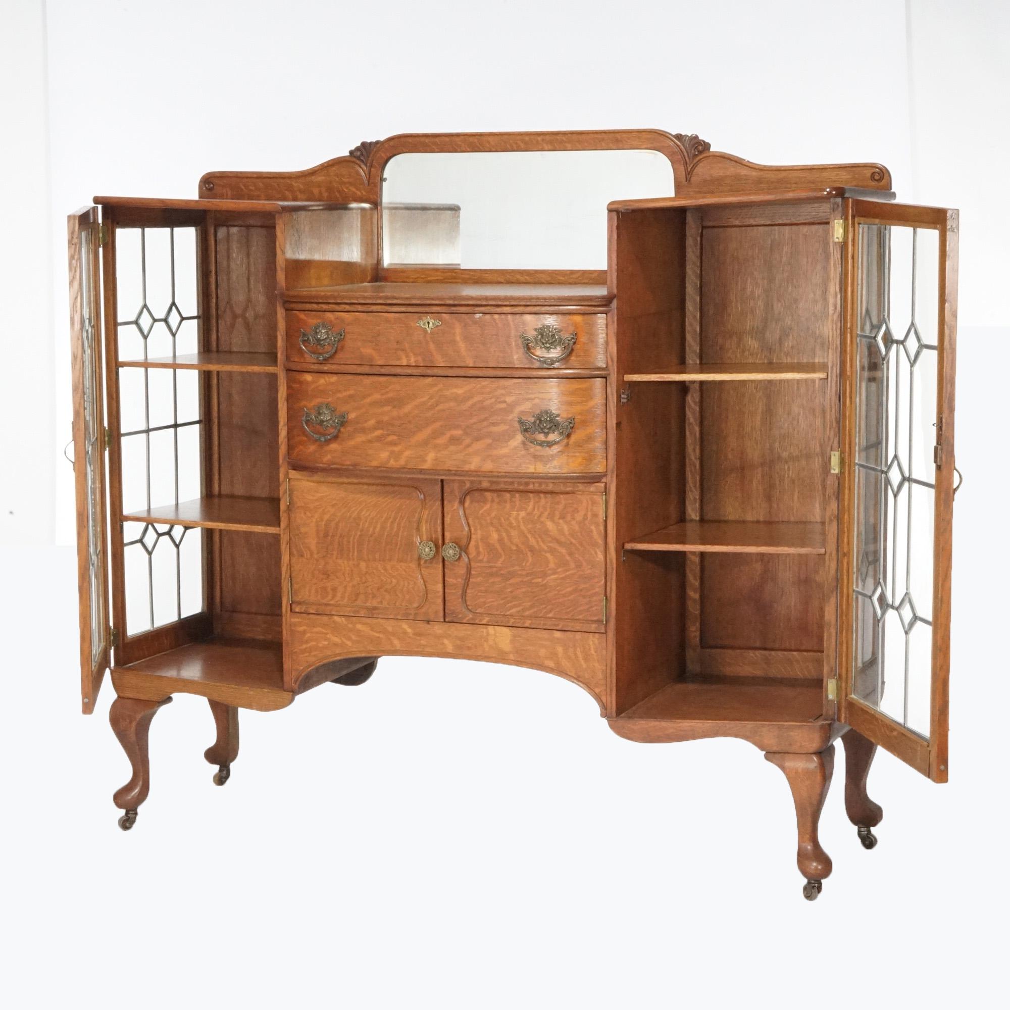 An antique buffet in the manner of RJ Horner offers quarter sawn oak construction with central mirrored backsplash bow-front over drawers and lower cabinet and having flanking leaded glass china cabinets with shelved interiors, raised on cabriole