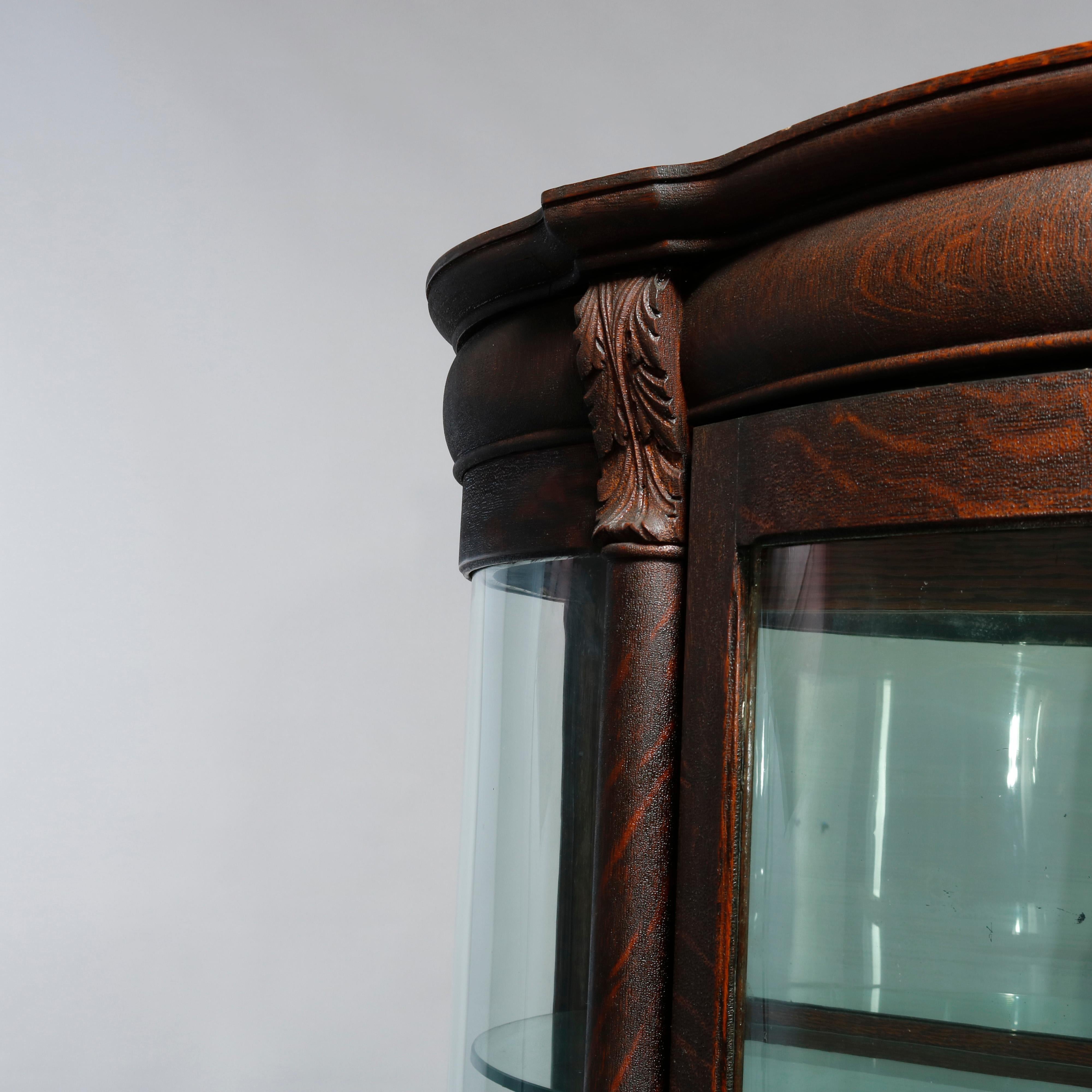 An antique china cabinet in the manner of RJ Horner offers quarter sawn oak frame with curved glass sides and single door opening to shelved and mirrored interior, raised on cabriole legs with carved paw feet, c1900.

Measures: 69