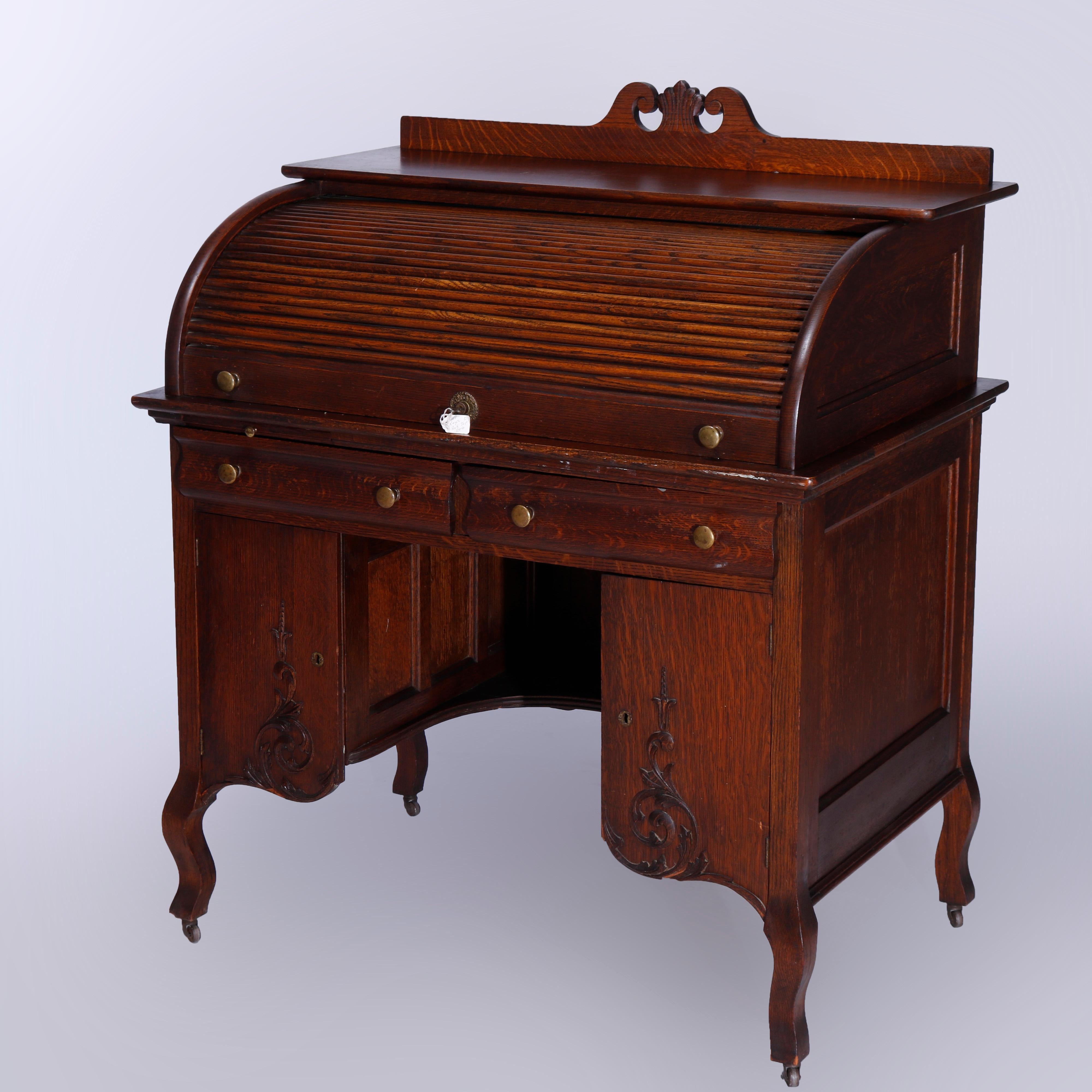 An antique ladies desk in the manner of R.J. Horner offers quarter sawn oak construction with broken arch backsplash having central foliate finial over roll top opening to writing surface and pigeon hole storage compartments, lower with double upper
