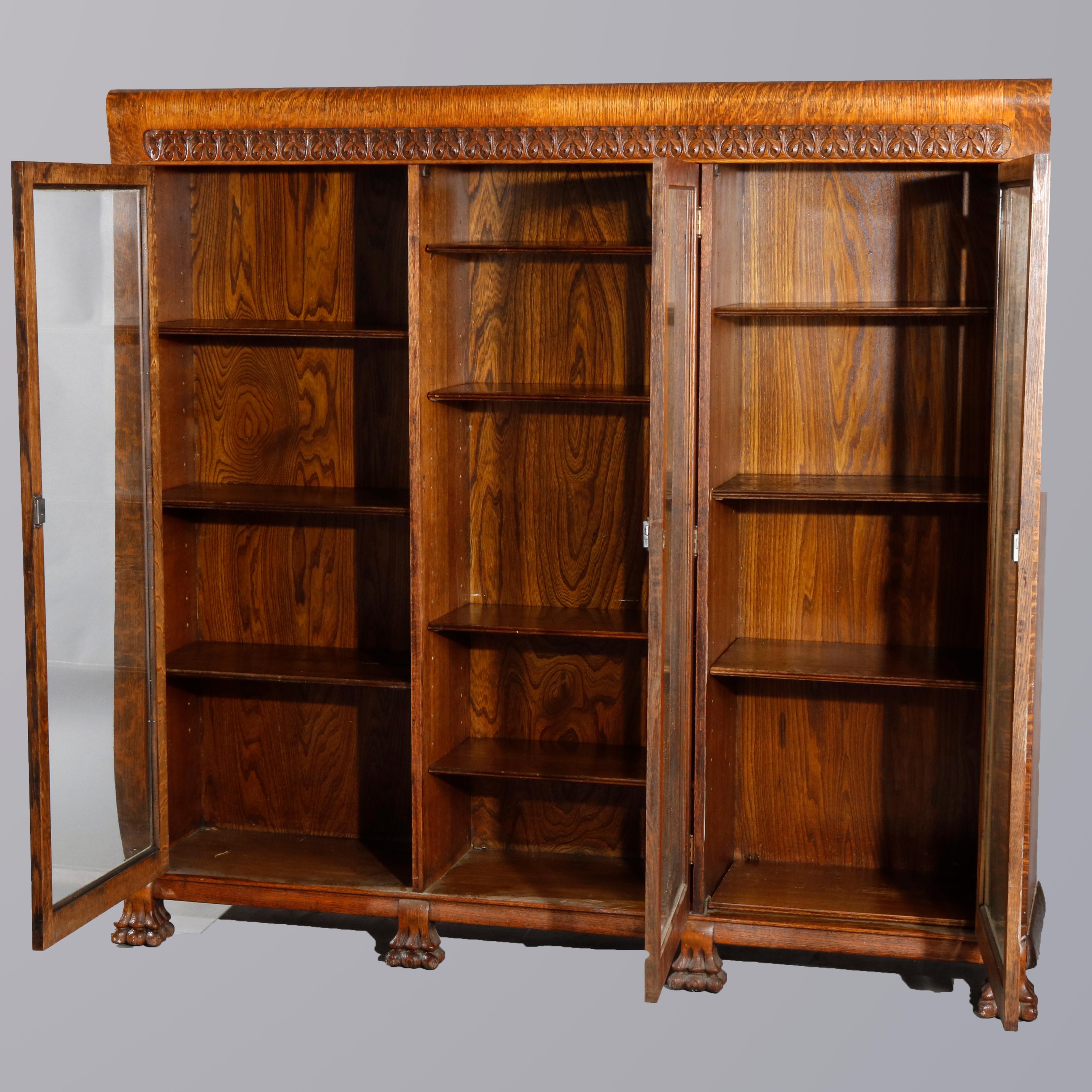 An antique RJ Horner bookcase offers quarter sawn oak construction with carved frieze surmounting triple glass doors opening to shelved interior and raised on carved paw feet, circa 1900.

Measures: 60