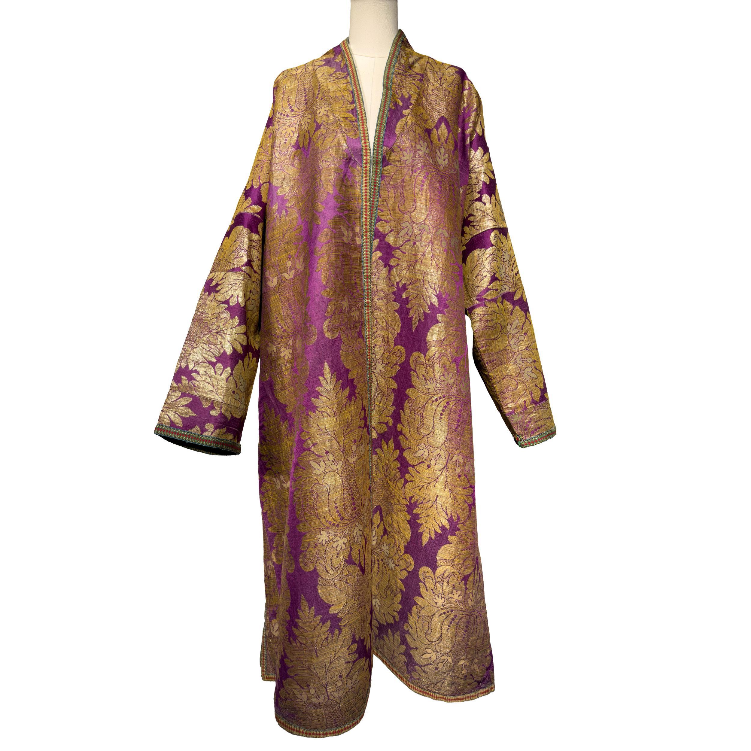 Un maestoso chapan da uomo uzbeko della metà del XIX secolo, tessuto in un ricco broccato di seta color prugna-viola con motivi damascati dorati su larga scala. Questo caratteristico motivo tessile, realizzato con fili di seta dai toni metallici,