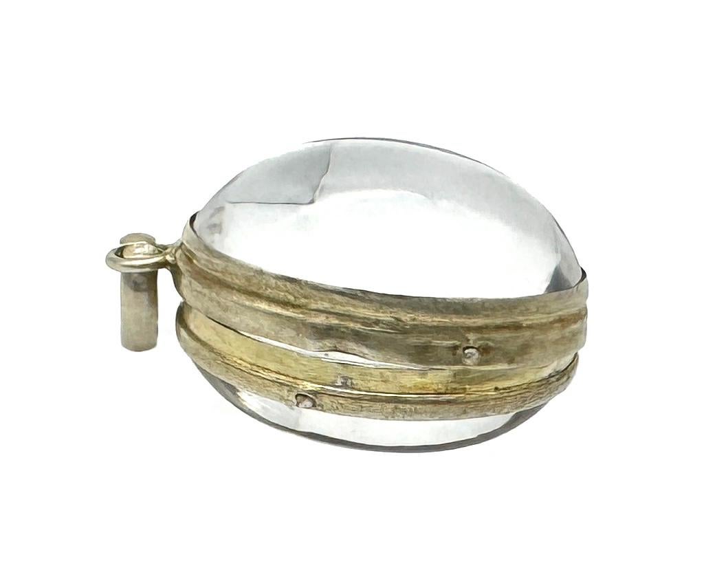 Questo splendido ciondolo in cristallo di rocca è stato creato nella seconda metà del XIX secolo, a giudicare dalla montatura in argento, intorno al 1860/1870.
Il medaglione ha la forma di un uovo. Due cabochon ovali identici di cristallo di rocca