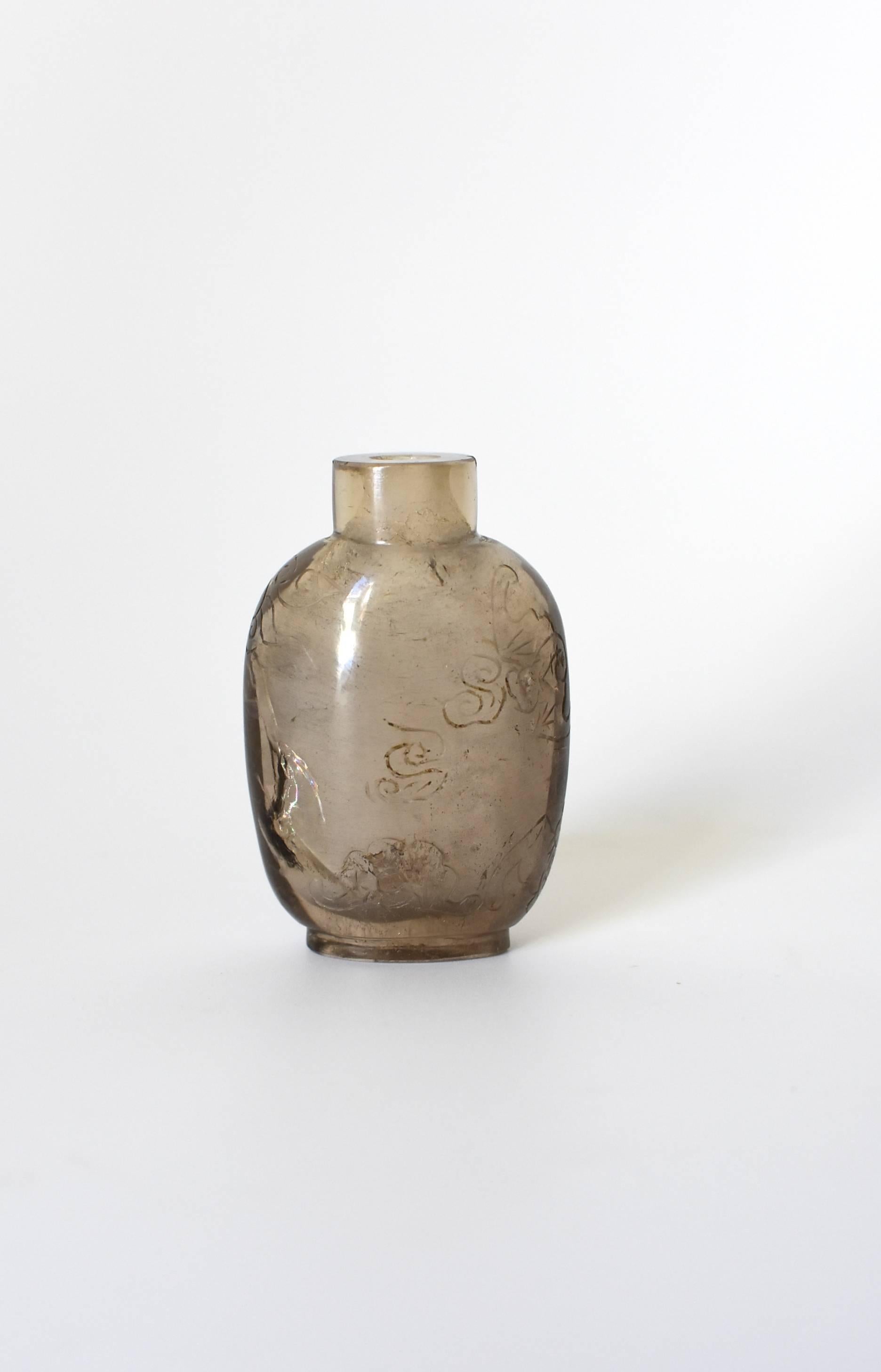 This is a 19th century, smoky quartz rock crystal Chinese snuff bottle. It is carved from a piece of natural crystal, hollowed out and polished to perfection. Cloud pattern on the exterior is simple and beautiful. There is a natural fissure in the