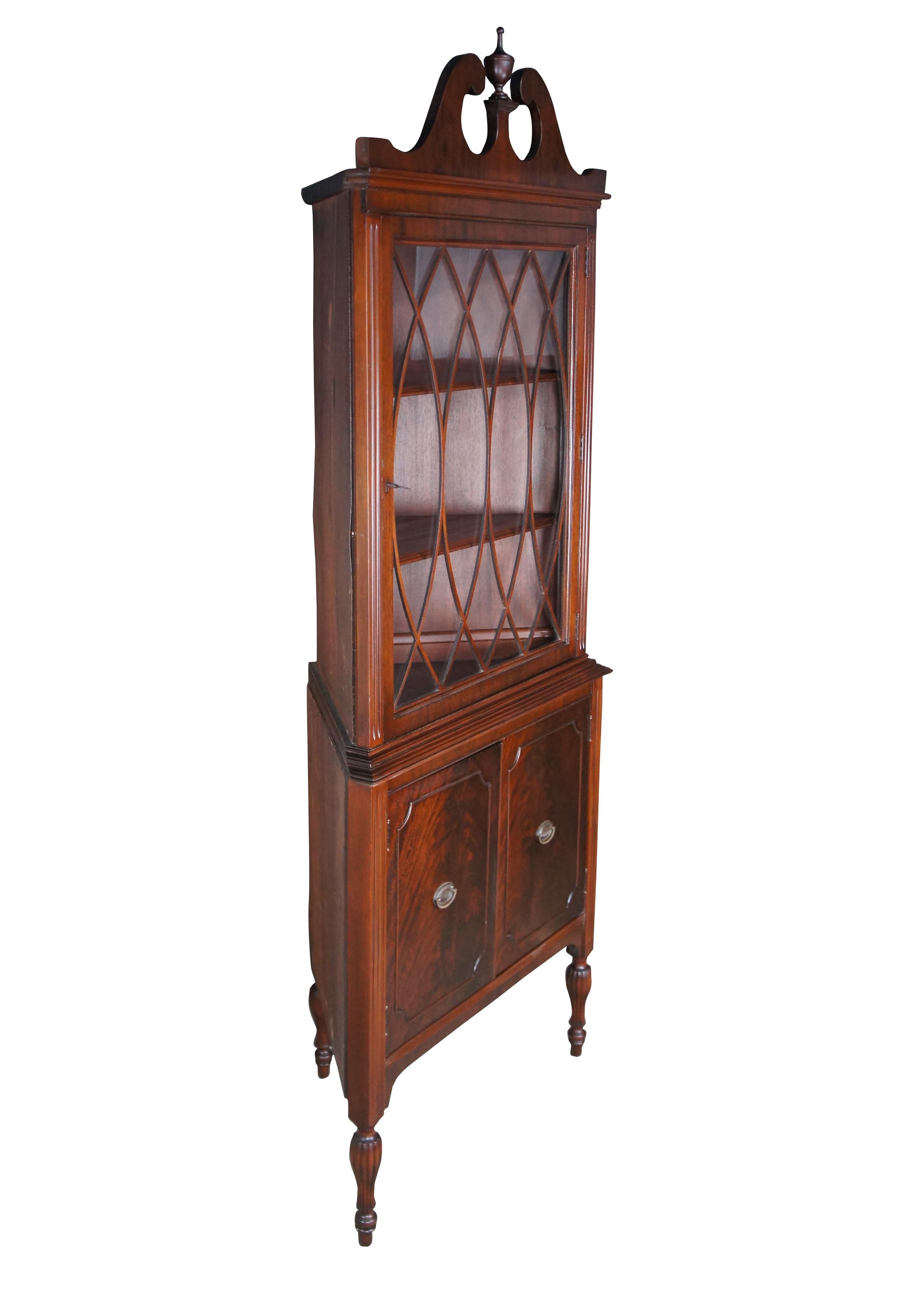 Antique Rockford Furniture Company B Line corner china cabinet / curio.  Made of mahogany featuring upper cabinet with lattice doors, fluted accents and serpentine open pediment crown with trophy finial over lower cabinet and tapered reeded legs