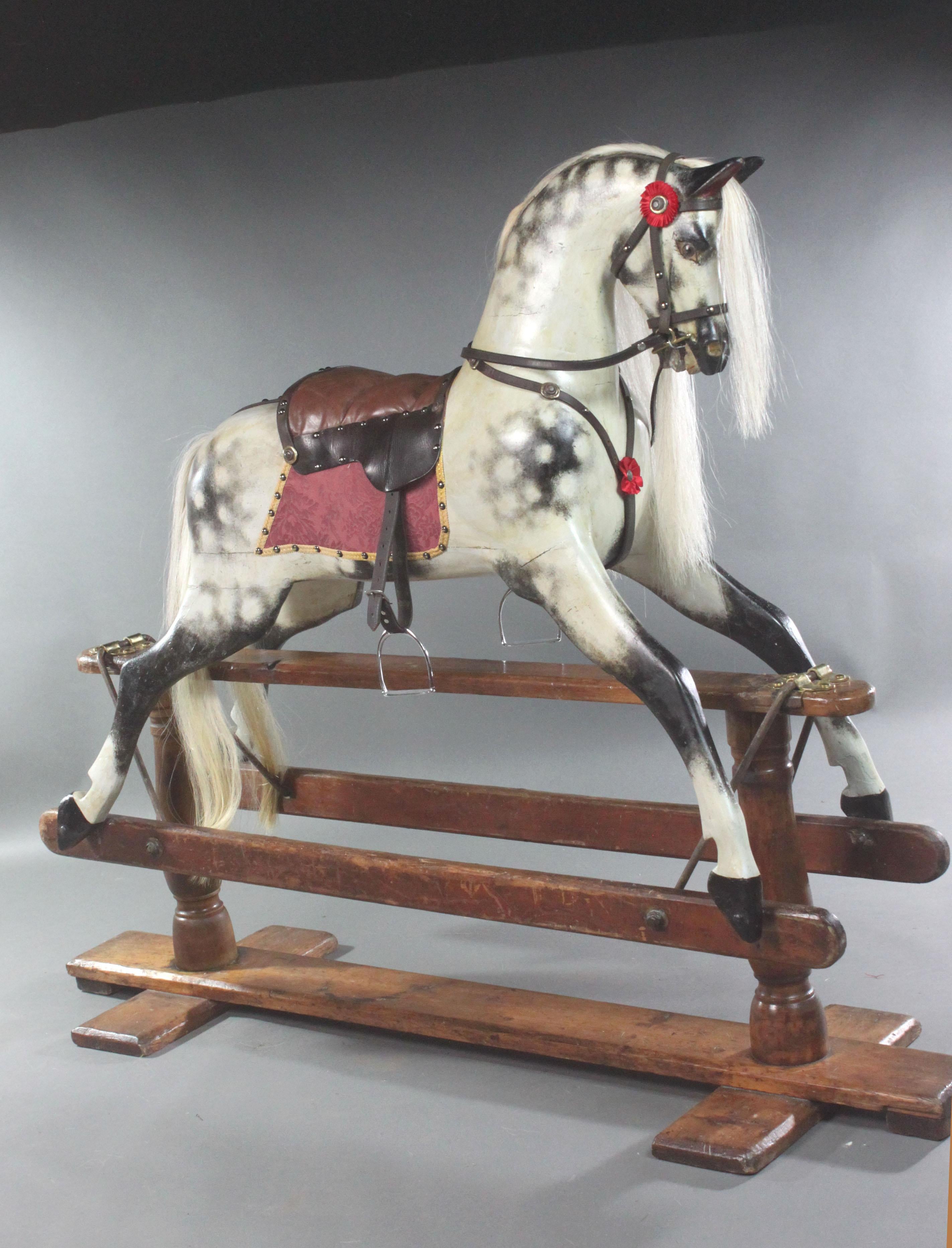 A handsome large carved wooden rocking horse by F.H.Ayres on its original stand with turned pillars and the head slightly tilted. The horse has been sensitively restored retaining much of its original paint and brass studs; we used old horse tack