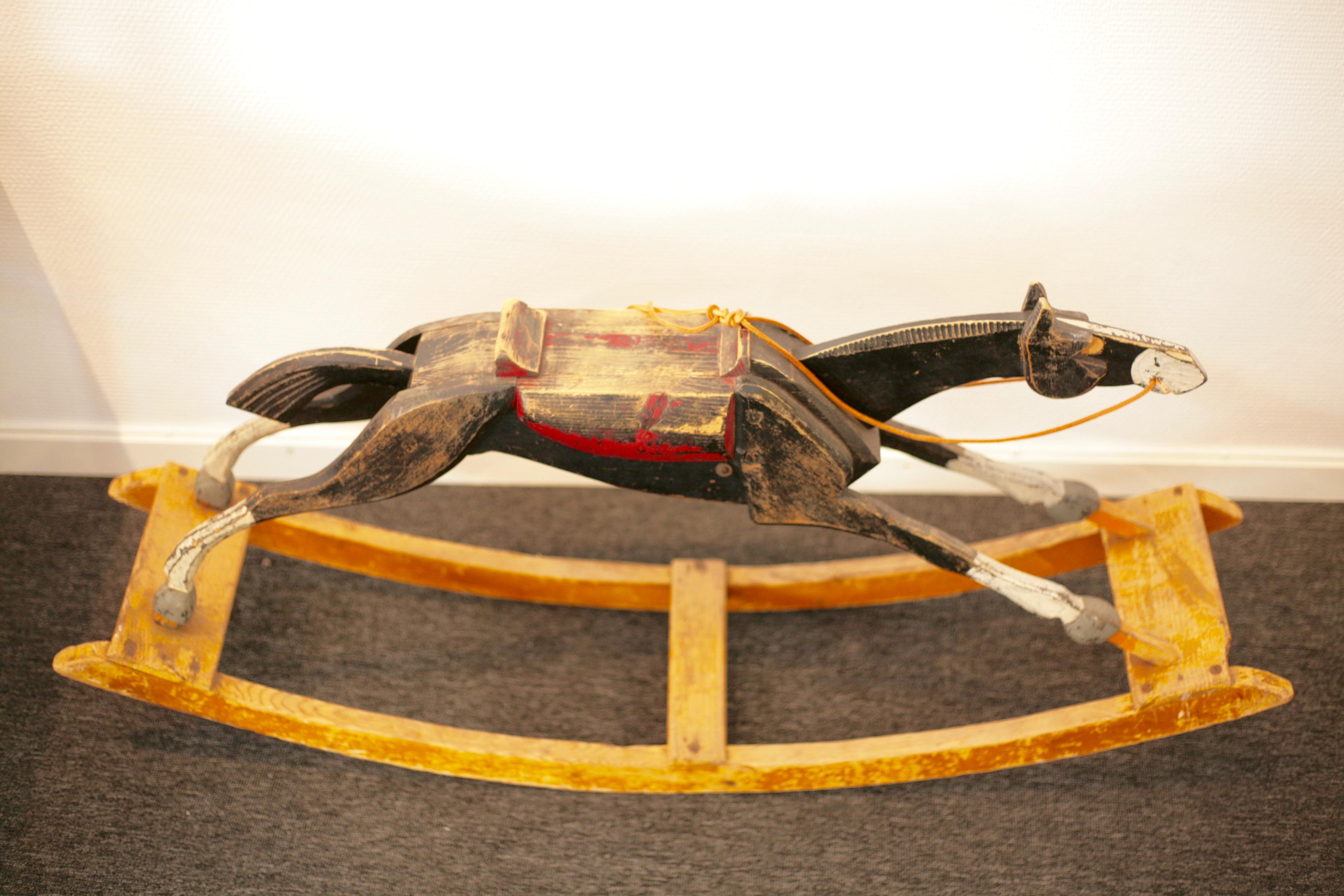 An antique black wooden rocking horse, circa 1900. In good vintage condition. Small chip to one of the front wooden boards. New leather reins.