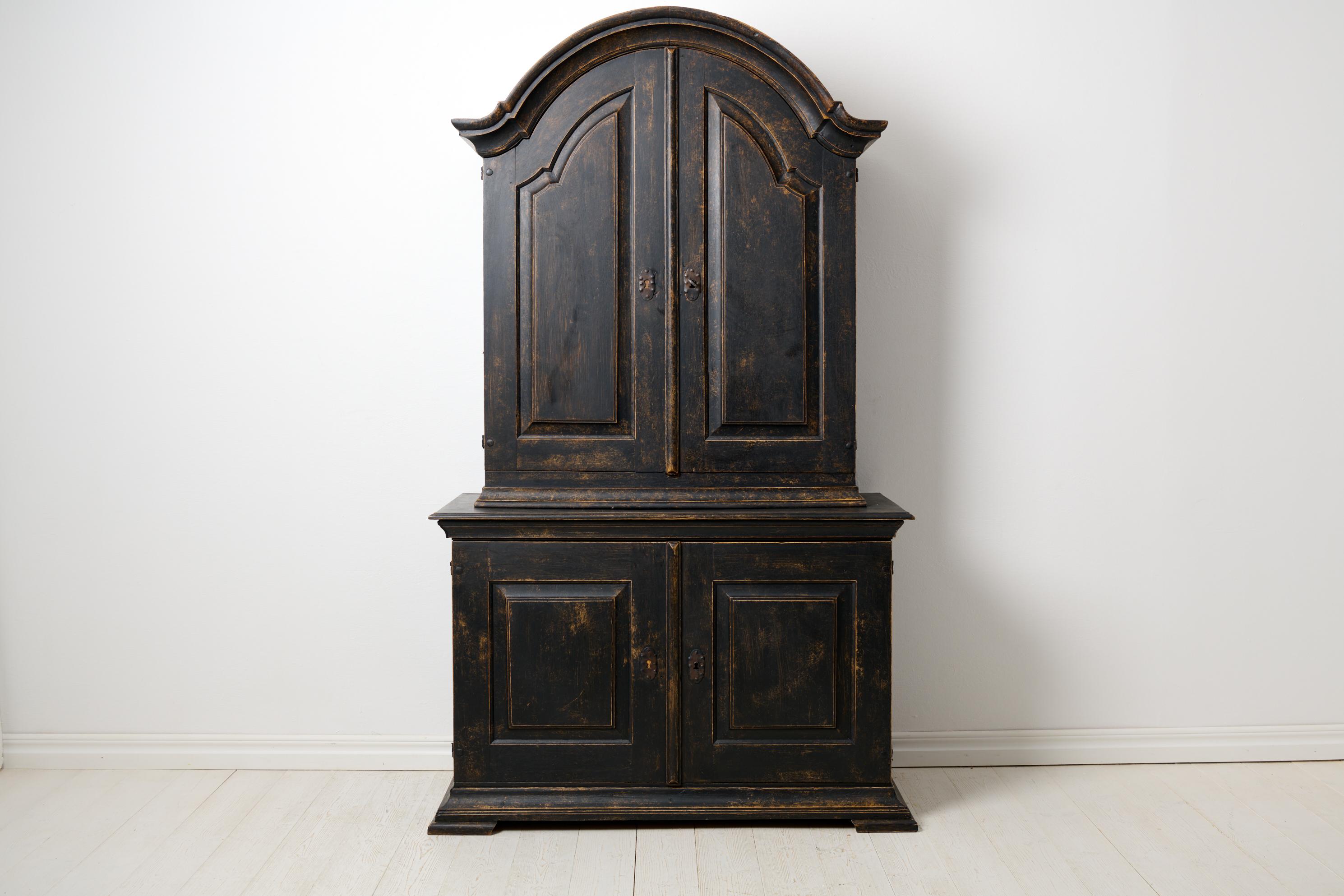 Antique Swedish rococo cabinet from around 1780. The cabinet is made in solid oak with distressed black paint. Made in two parts with the original and functional lock and key. The interior is bare wood and always has been. The lower cabinet measures