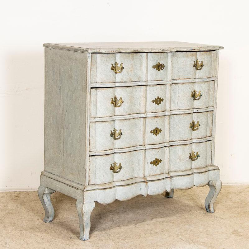 The strong visual appeal of this lovely large rococo chest of drawers is due to the newer, professionally applied layered blue painted finish that accents the contours of the top and each of the serpentine drawer fronts. Where the paint has been
