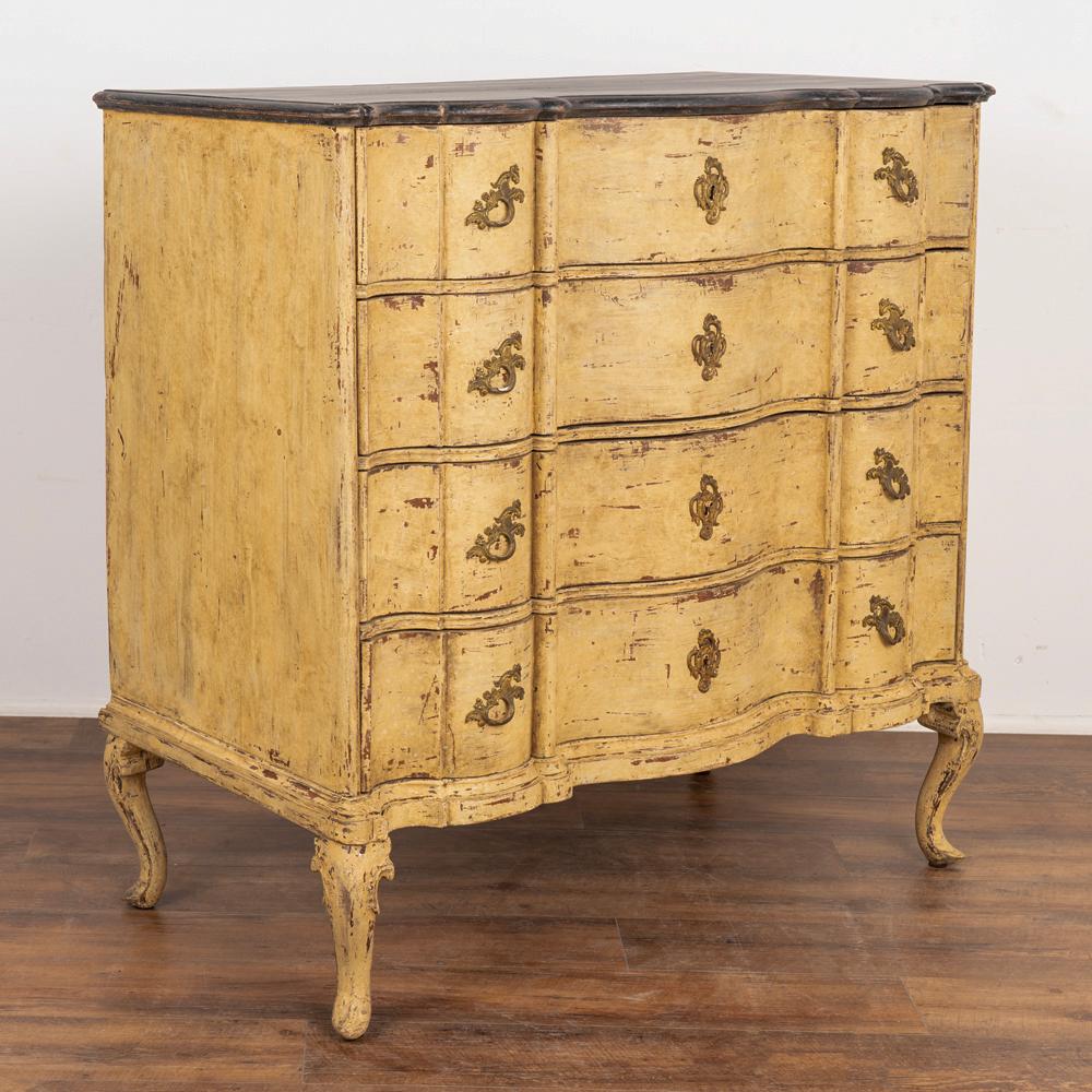 Large rococo oak chest of 4 drawers with serpentine front resting on cabriolet feet.
The four drawers each have 2 brass pulls and key hole bracket. 
Newer professionally applied layered paint of burnished yellow, with undertones of brown and gray